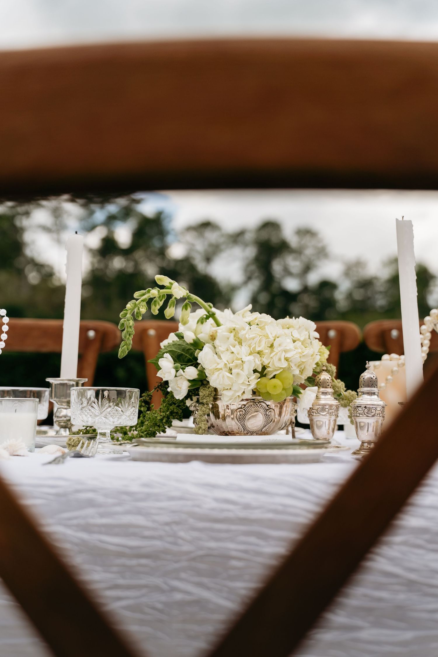 White floral centerpieces and candles line an elegant wedding reception table with a crisp white tablecloth.