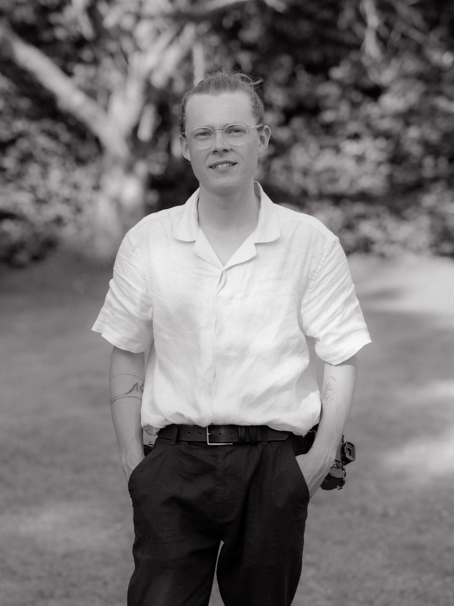 Person in white polo shirt and dark pants stands on grass in black and white photo.
