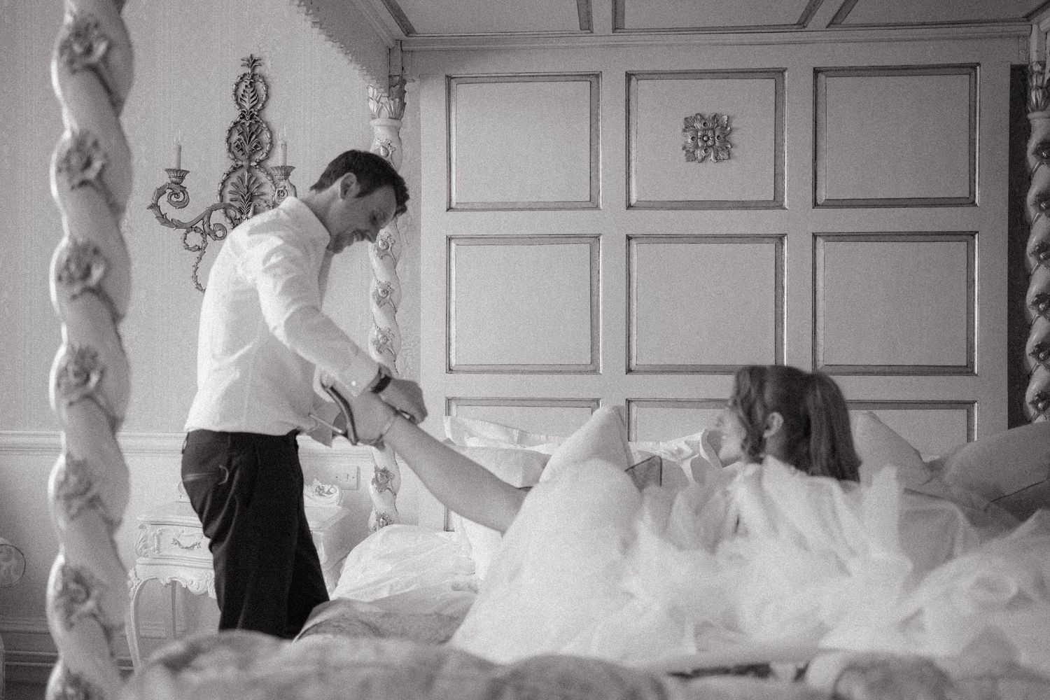 Black and white photo showing preparation with voluminous white dress fabric in an elegant room.