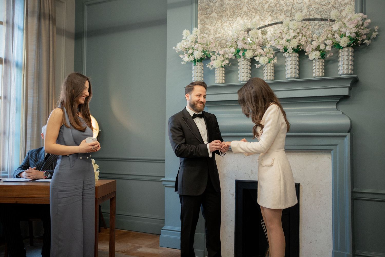 Couple dancing in an elegant blue-walled room with ornate white floral decorations above.