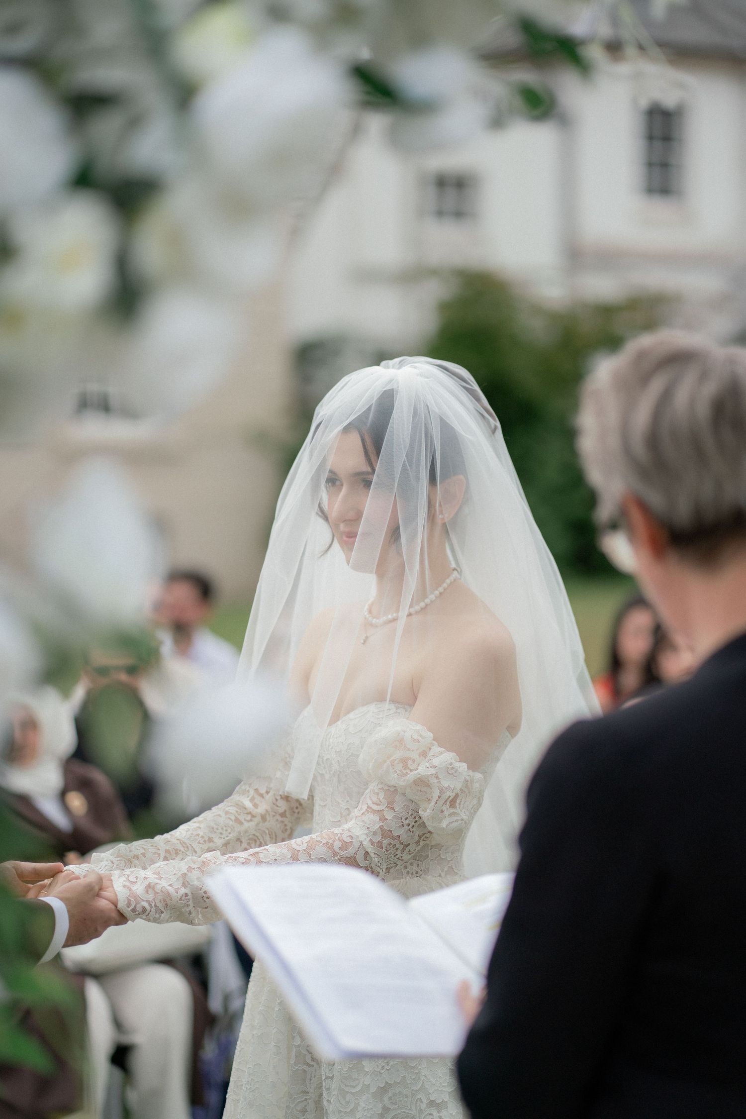 Side view of wedding ceremony proceedings with guests and floral decorations.