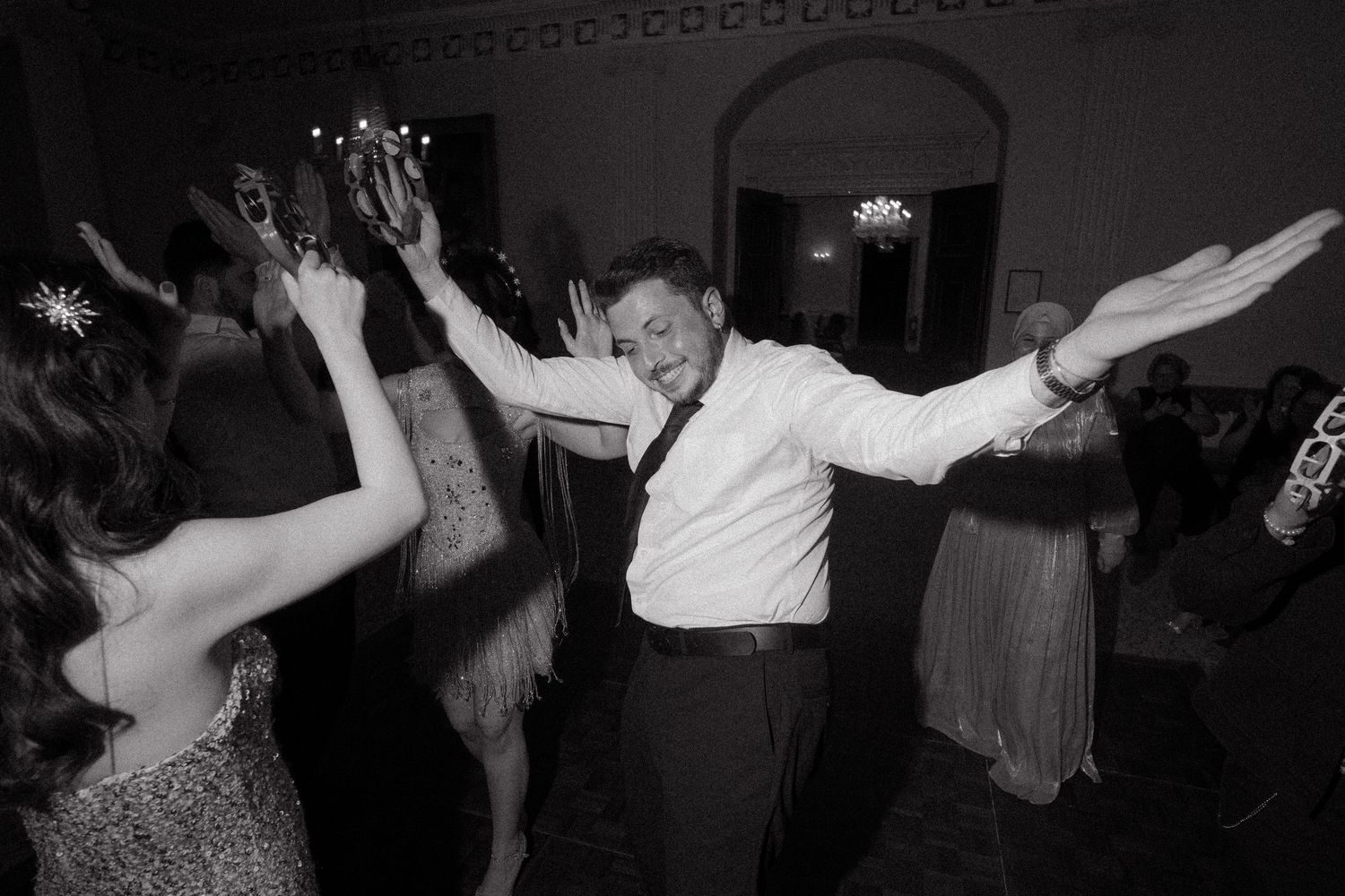 Wedding guests dancing energetically in dimly lit reception venue.