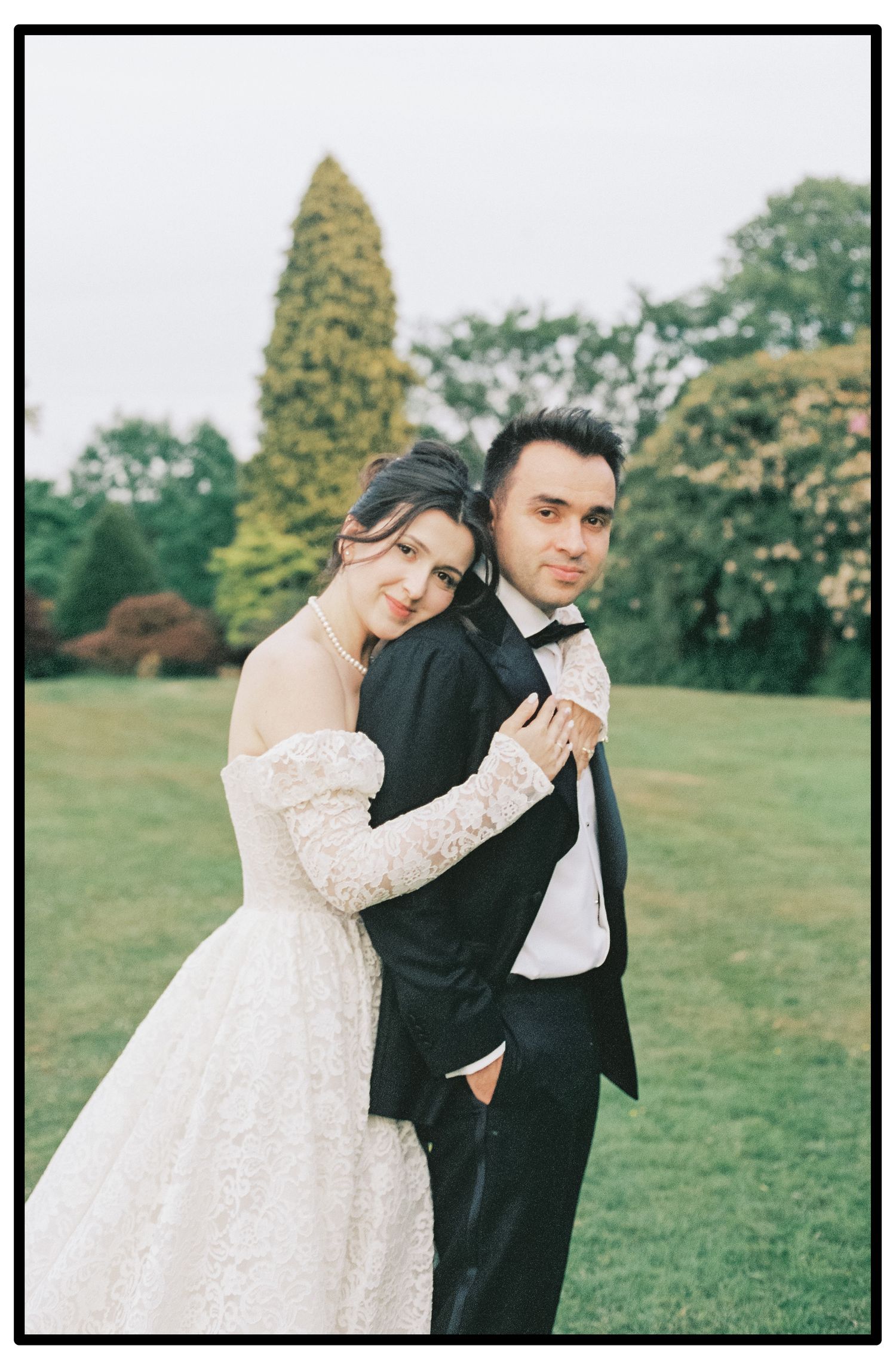 Intimate wedding portraits of a couple in formal attire posing in a lush garden setting.