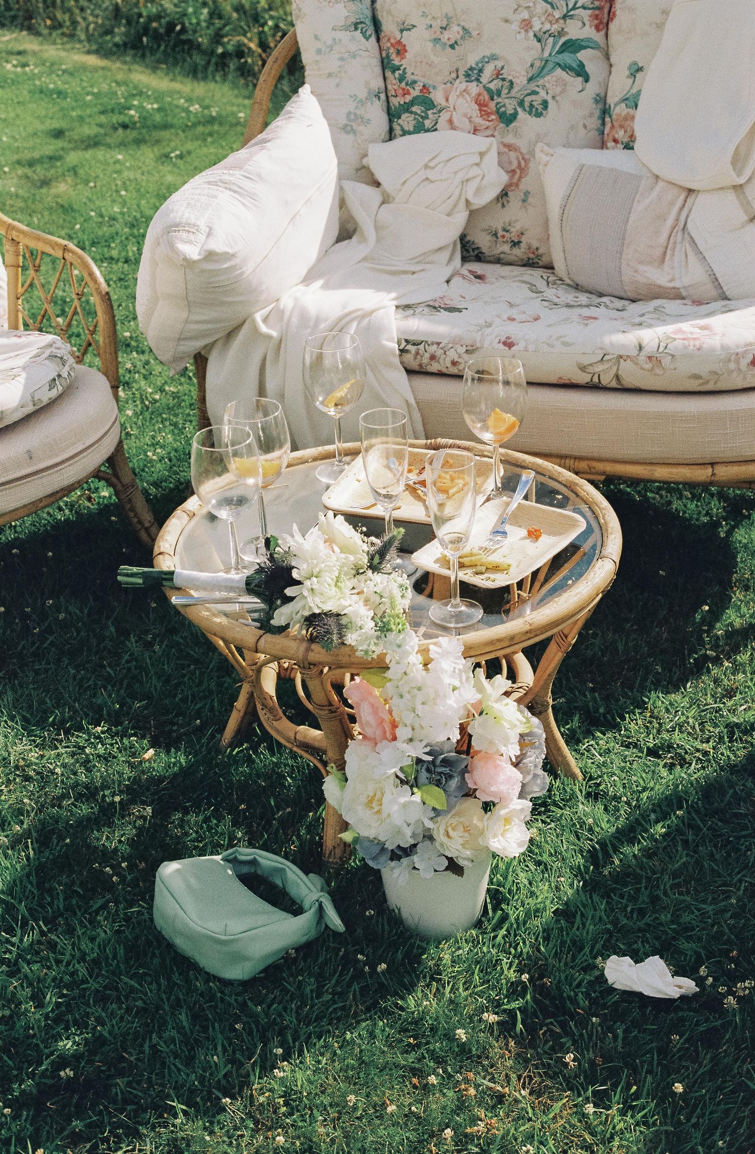 Vintage-style outdoor lounge furniture with floral arrangements and champagne glasses on a table.