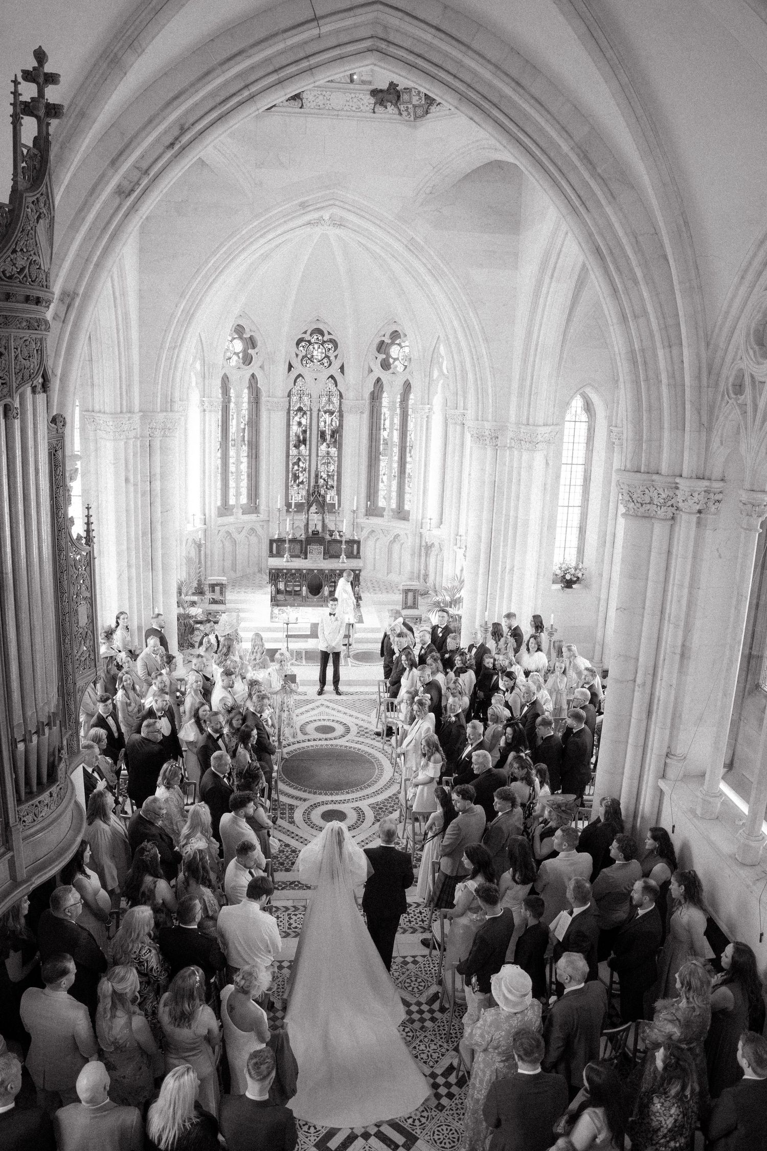 Black and white photo of wedding ceremony in Gothic cathedral with vaulted ceilings and arches.