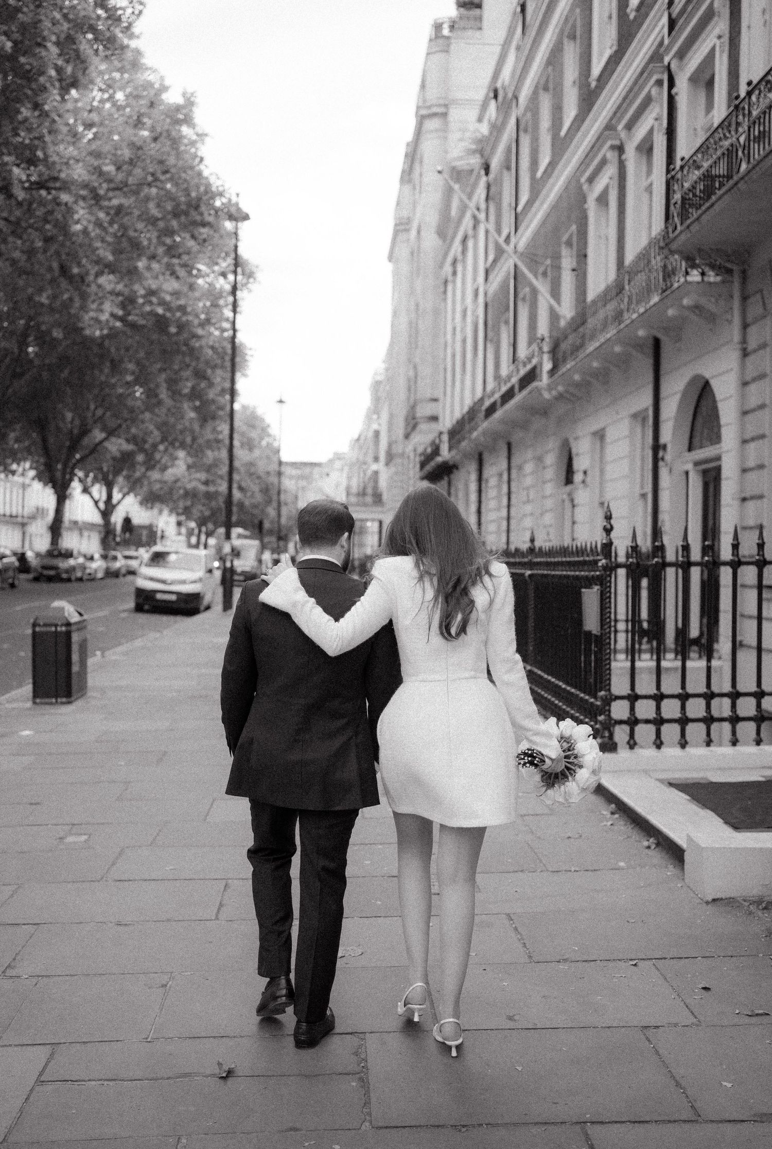 Couple walking down an elegant London street lined with classic architecture.