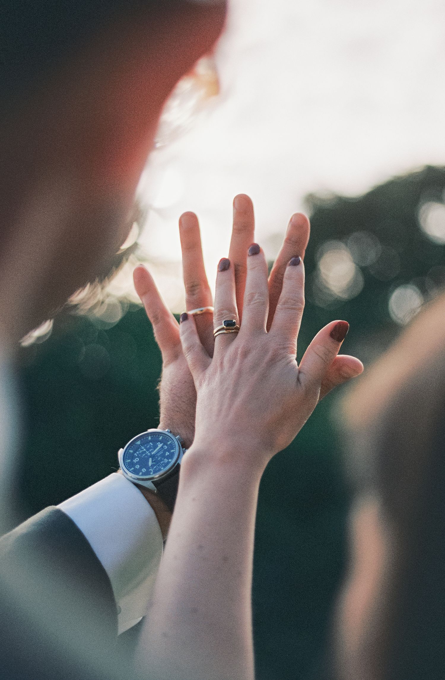 Raised hands reaching upward against a blurred green background with soft bokeh lighting effects.
