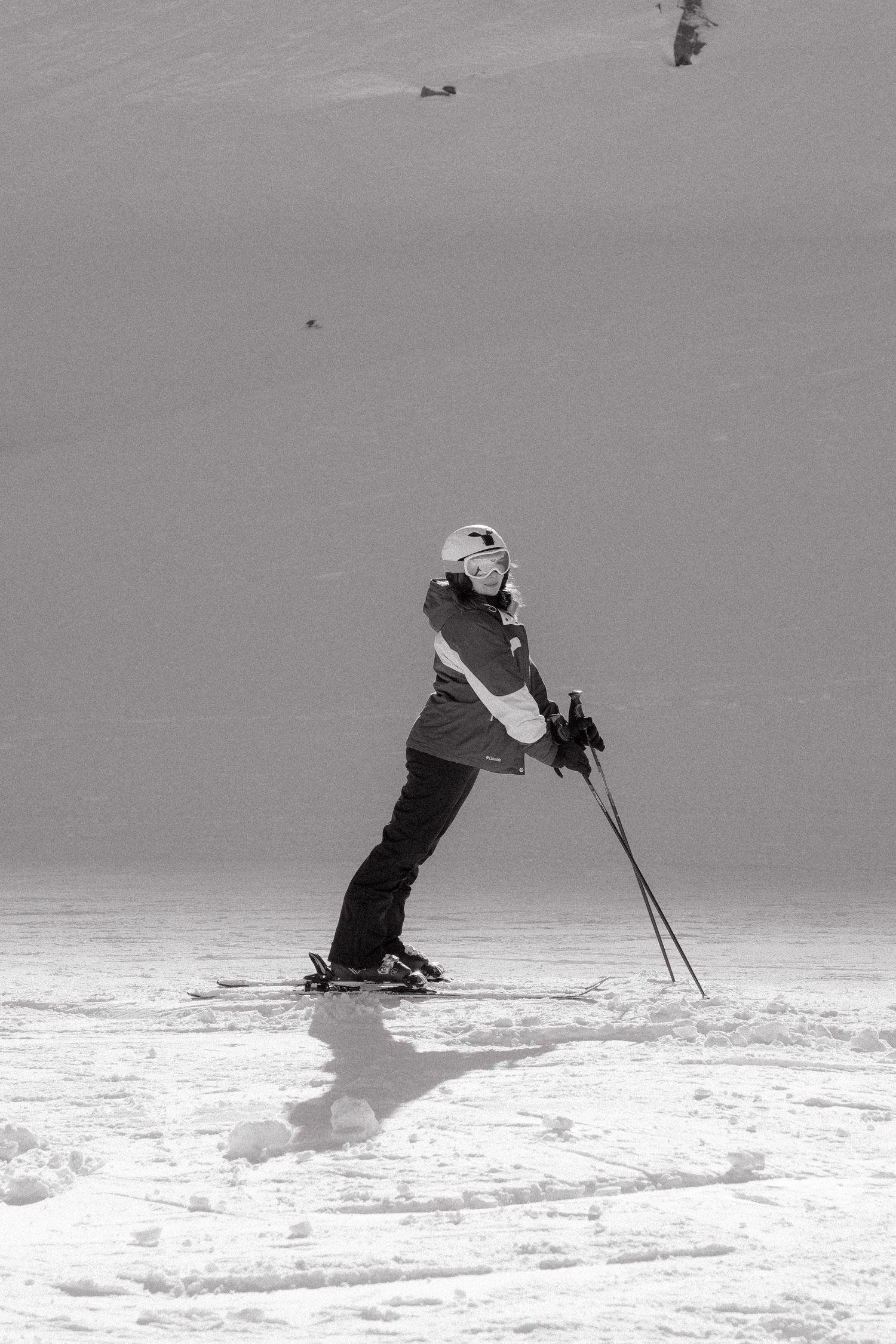 A sequence of four black and white photos showing a skier carving smooth turns down a snowy slope.