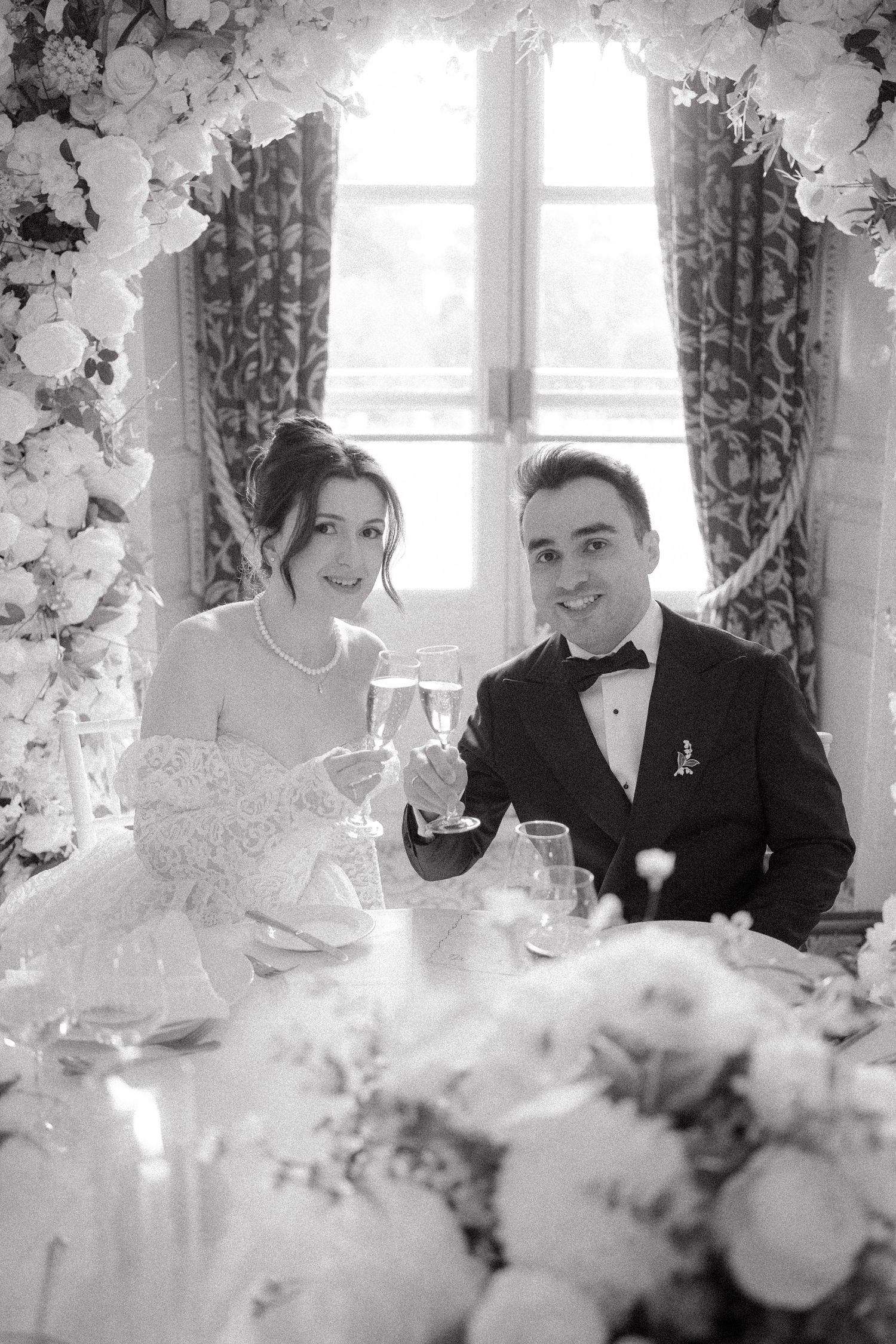 Wedding party dining at an elegantly decorated table with floral centerpieces.