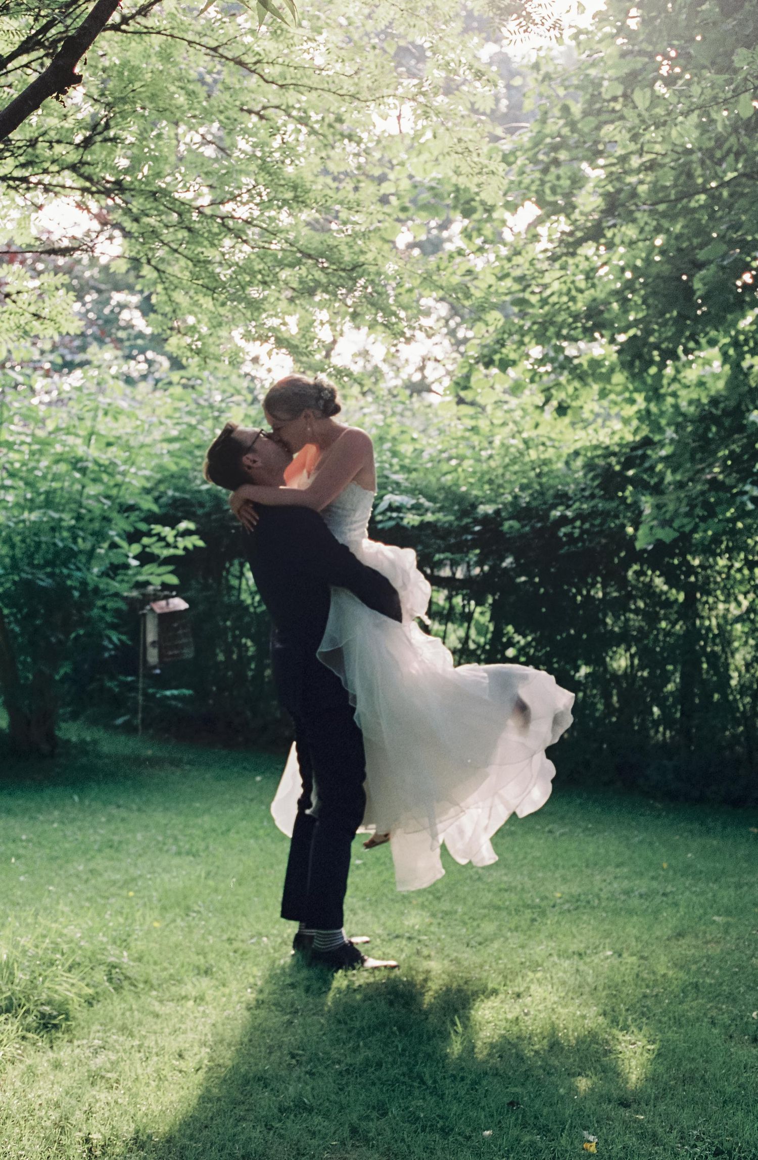 A couple dancing together outdoors in a garden setting with flowing white dress movement.