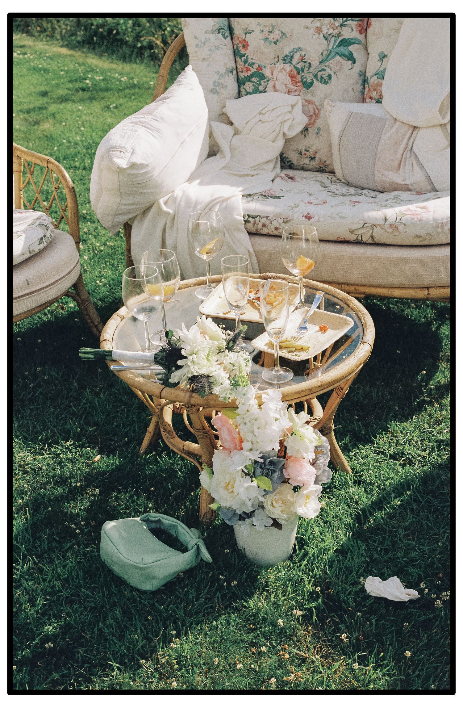 Vintage floral sofa and table arrangement in a garden setting with delicate white flower bouquets and soft decor elements.