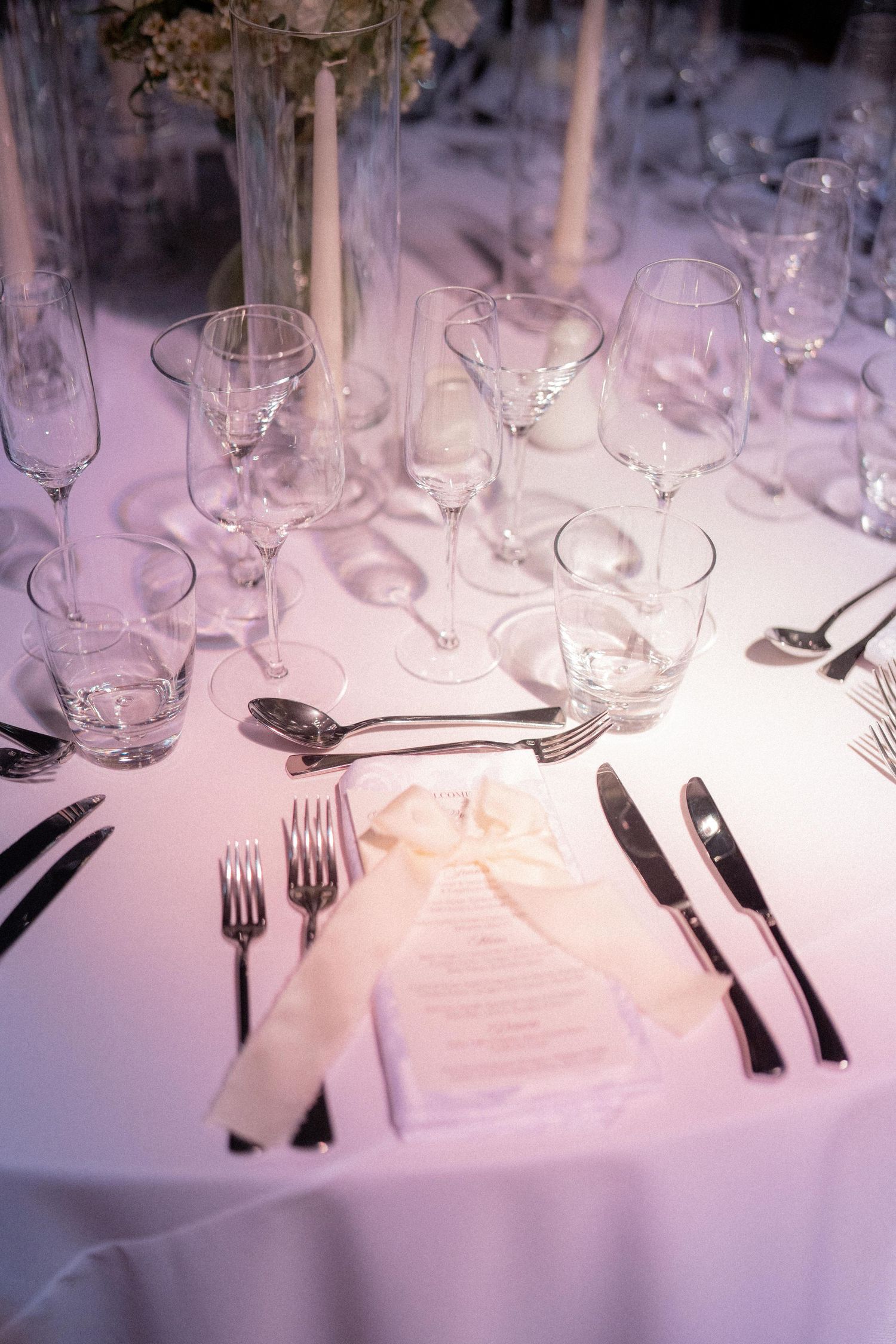 Elegant wedding reception table setting with crystal glasses and formal place settings.
