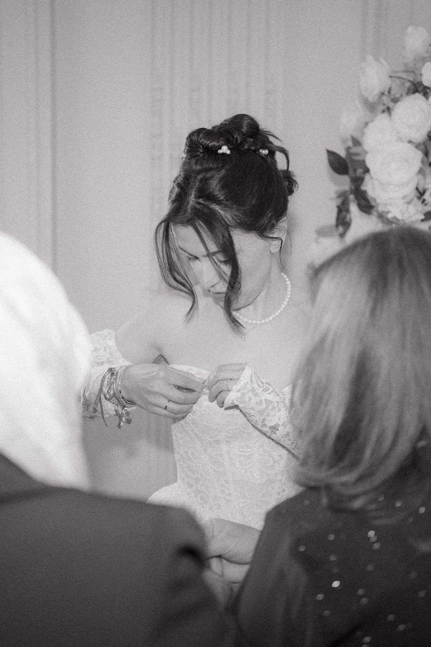 A candid black and white moment during wedding preparations showing delicate lace details.