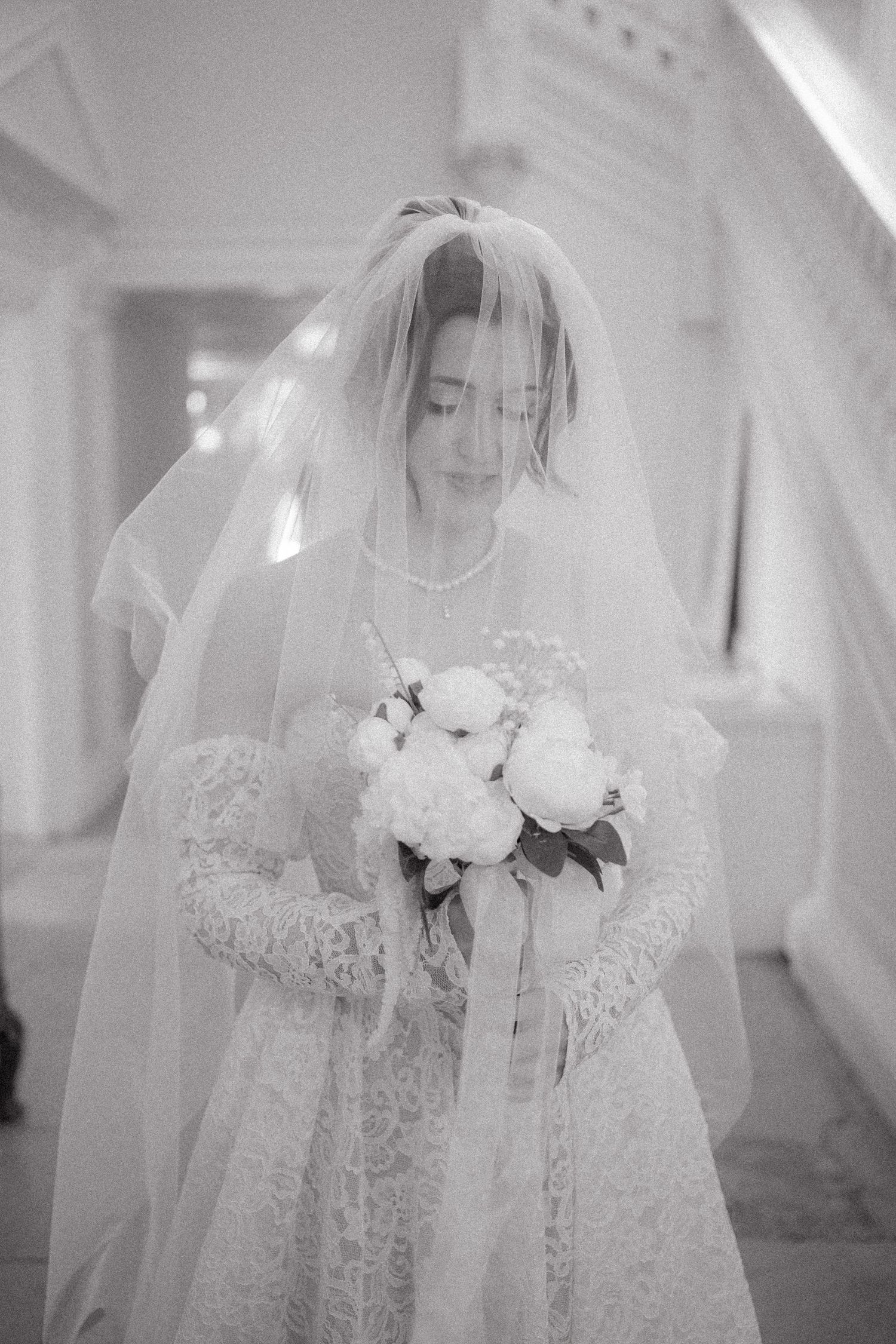 Ethereal black and white photos of a bride in a lace dress and flowing veil.