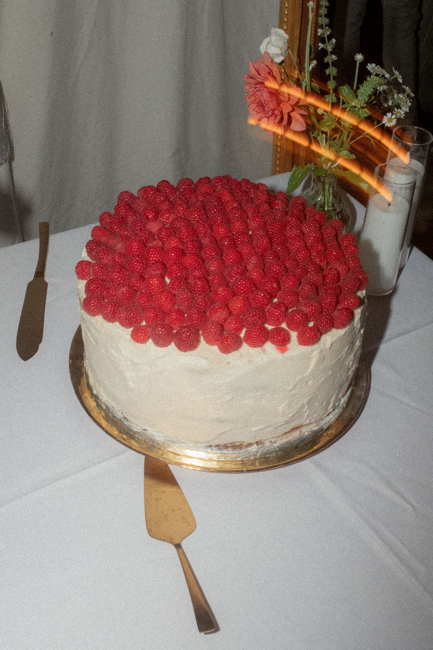 A white wedding cake decorated with fresh red raspberries on top.