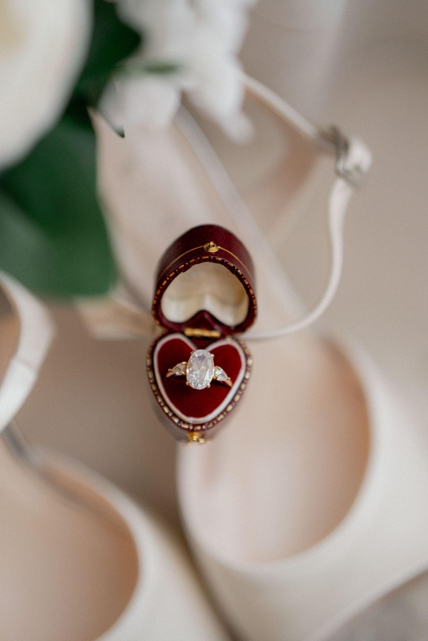 Diamond engagement rings displayed in burgundy ring boxes with floral elements.