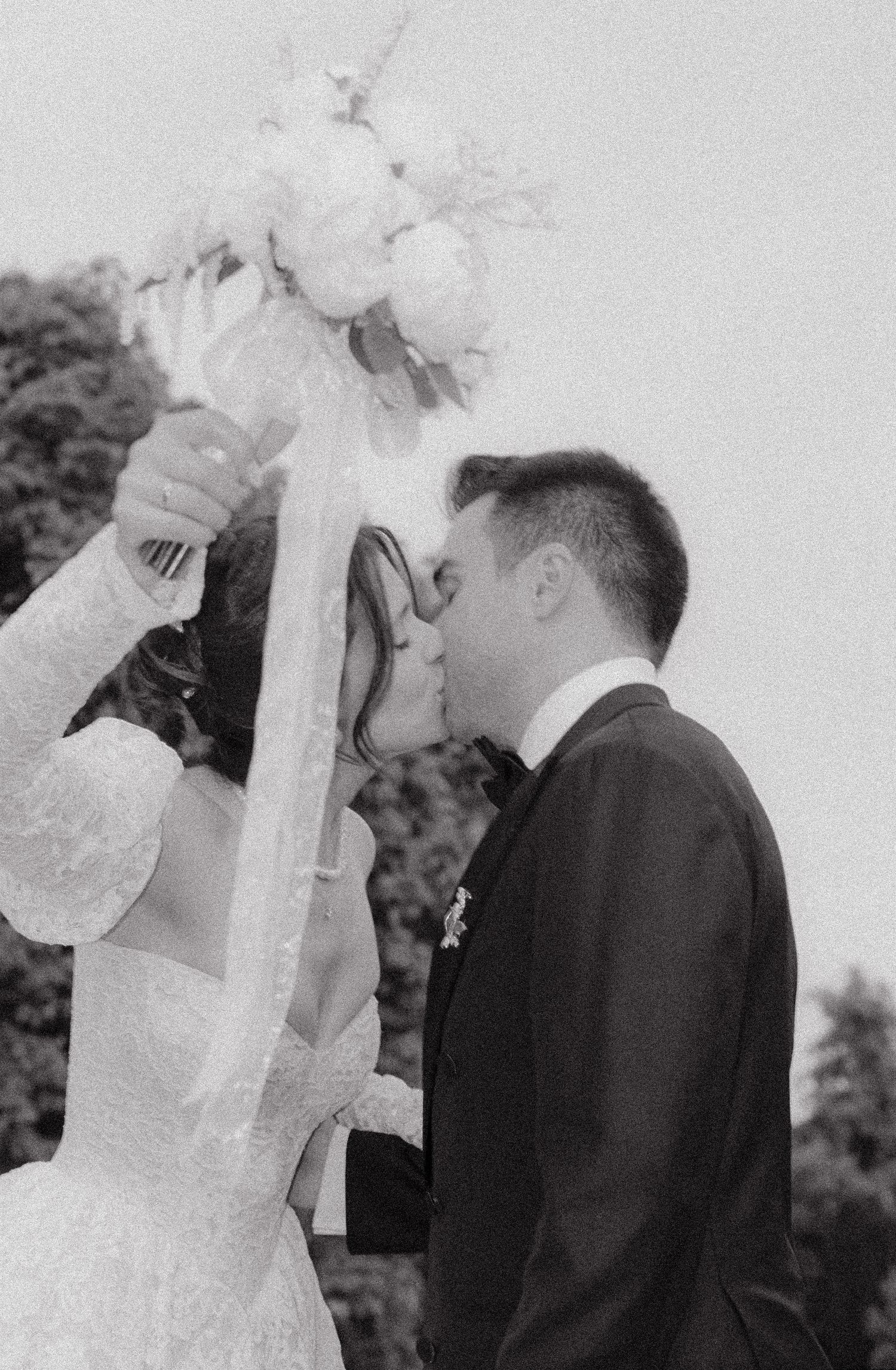 Black and white intimate wedding moment captured between couple in formal attire.