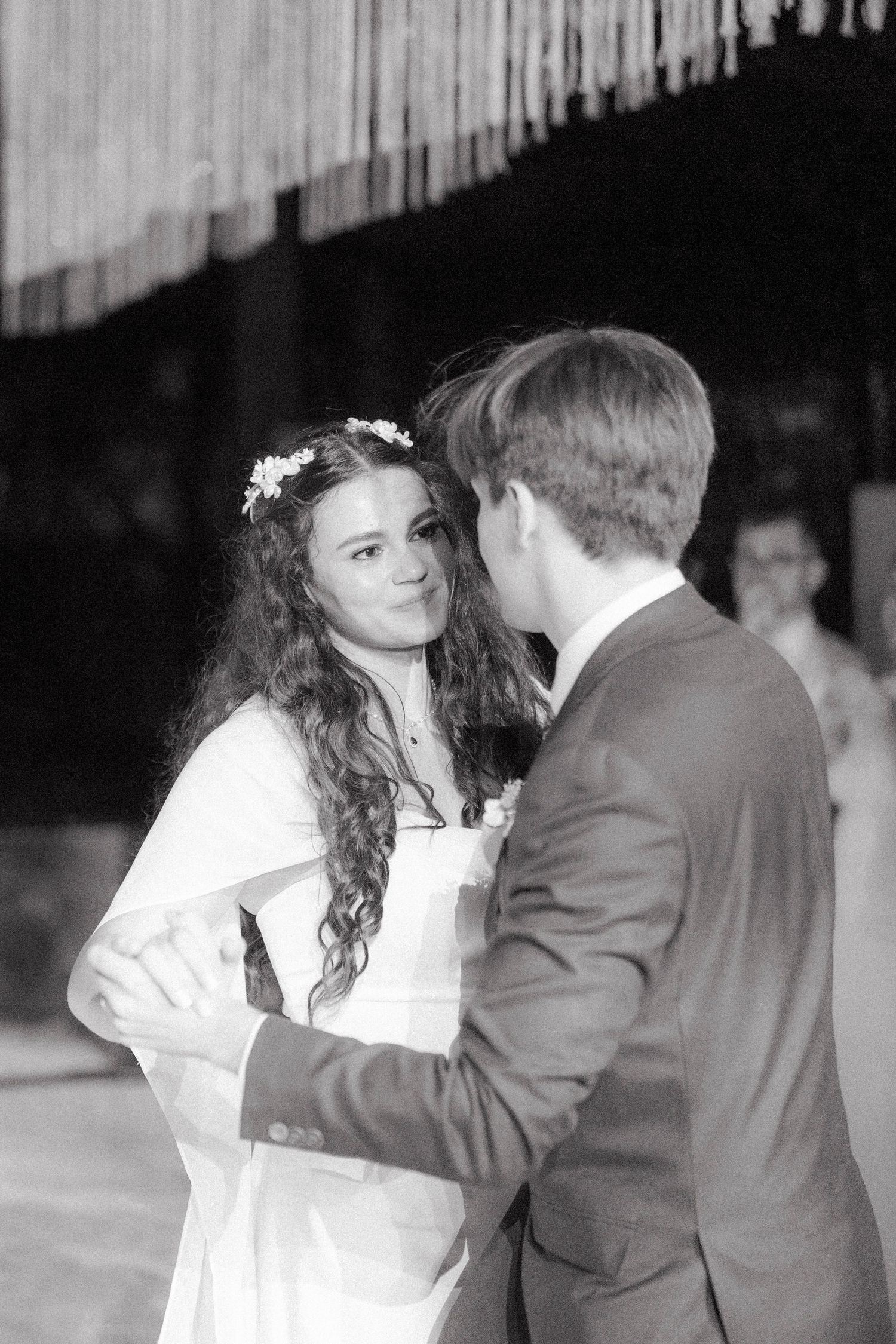 Black and white photo of bride with flower crown sharing first dance with groom.