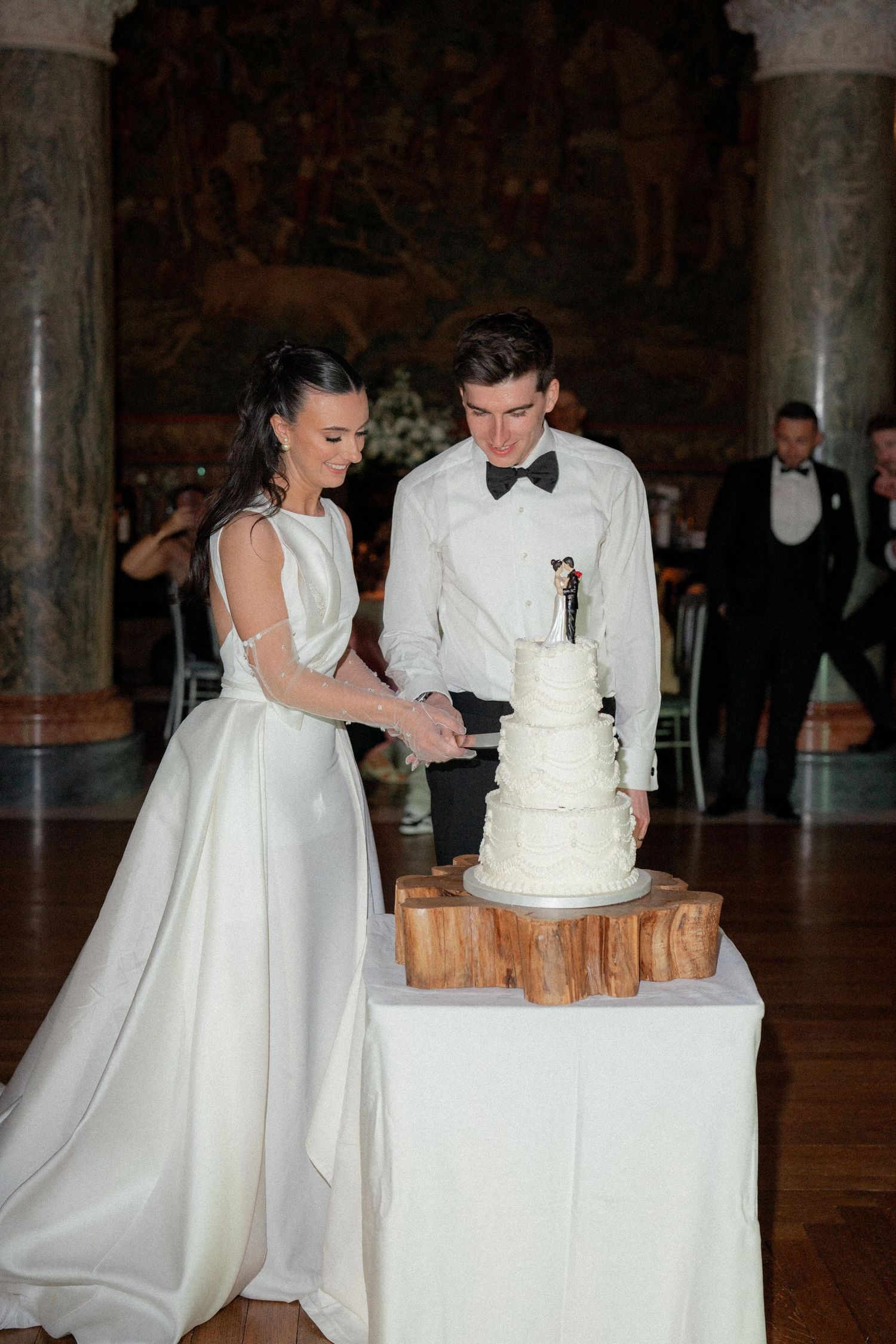 Wedding couple in white attire cutting their traditional white wedding cake at the reception.