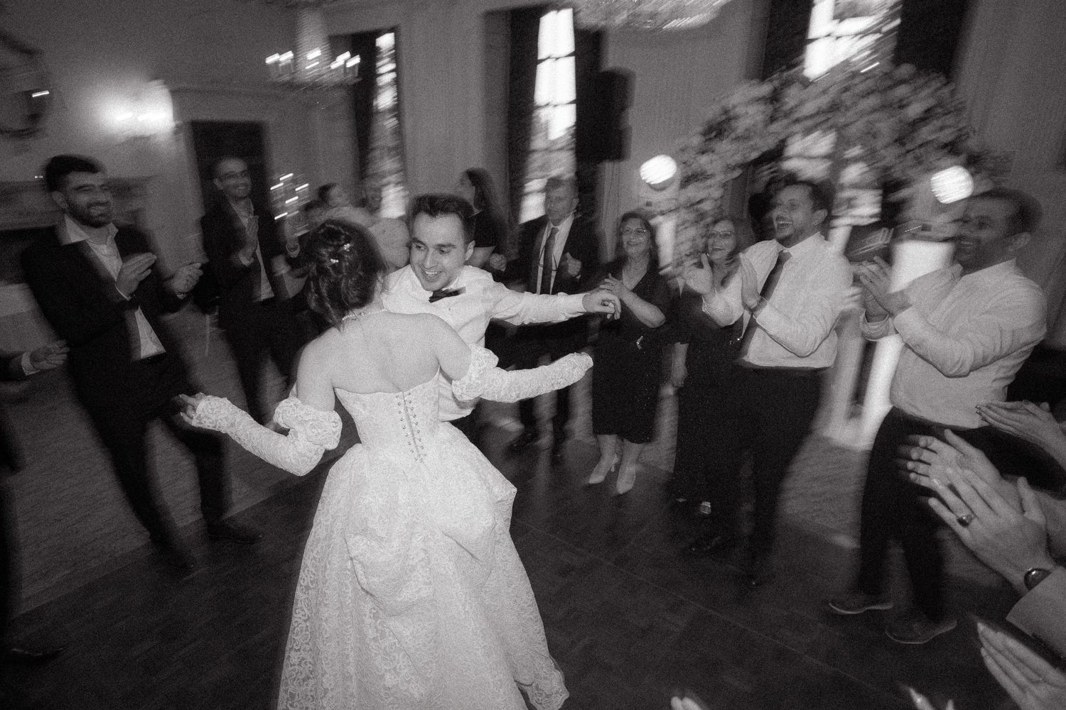 Lively dance celebration at wedding reception with guests in formal attire.