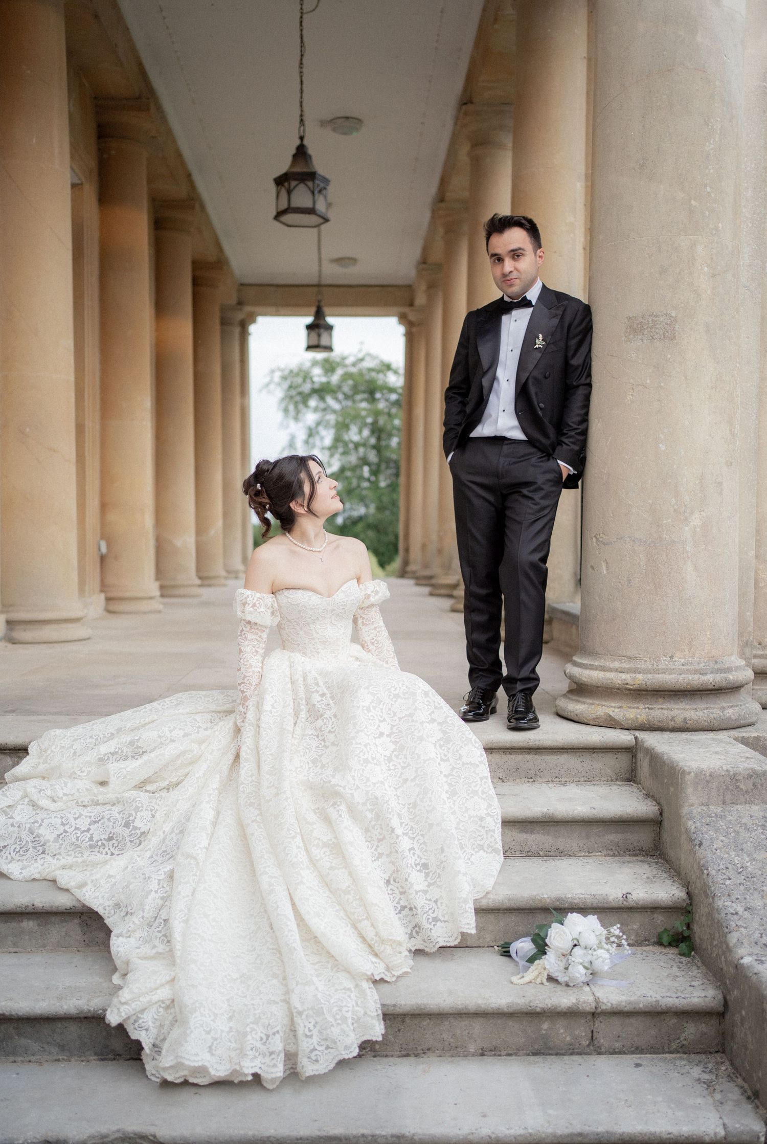 A romantic wedding portrait on columned steps with dramatic architectural details.