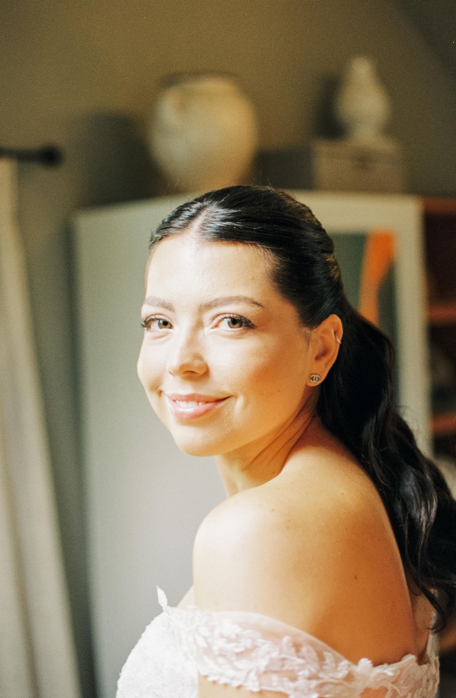 Close-up portrait of a bride wearing an off-shoulder dress and smiling warmly.