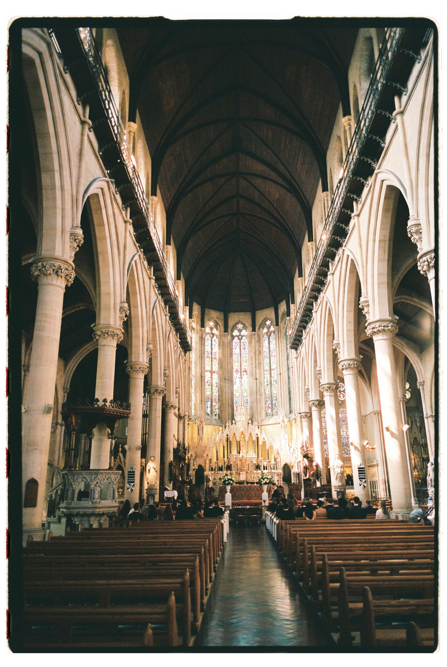 Stunning Gothic cathedral interior with soaring arched ceilings, stone columns, and ornate altar during wedding.
