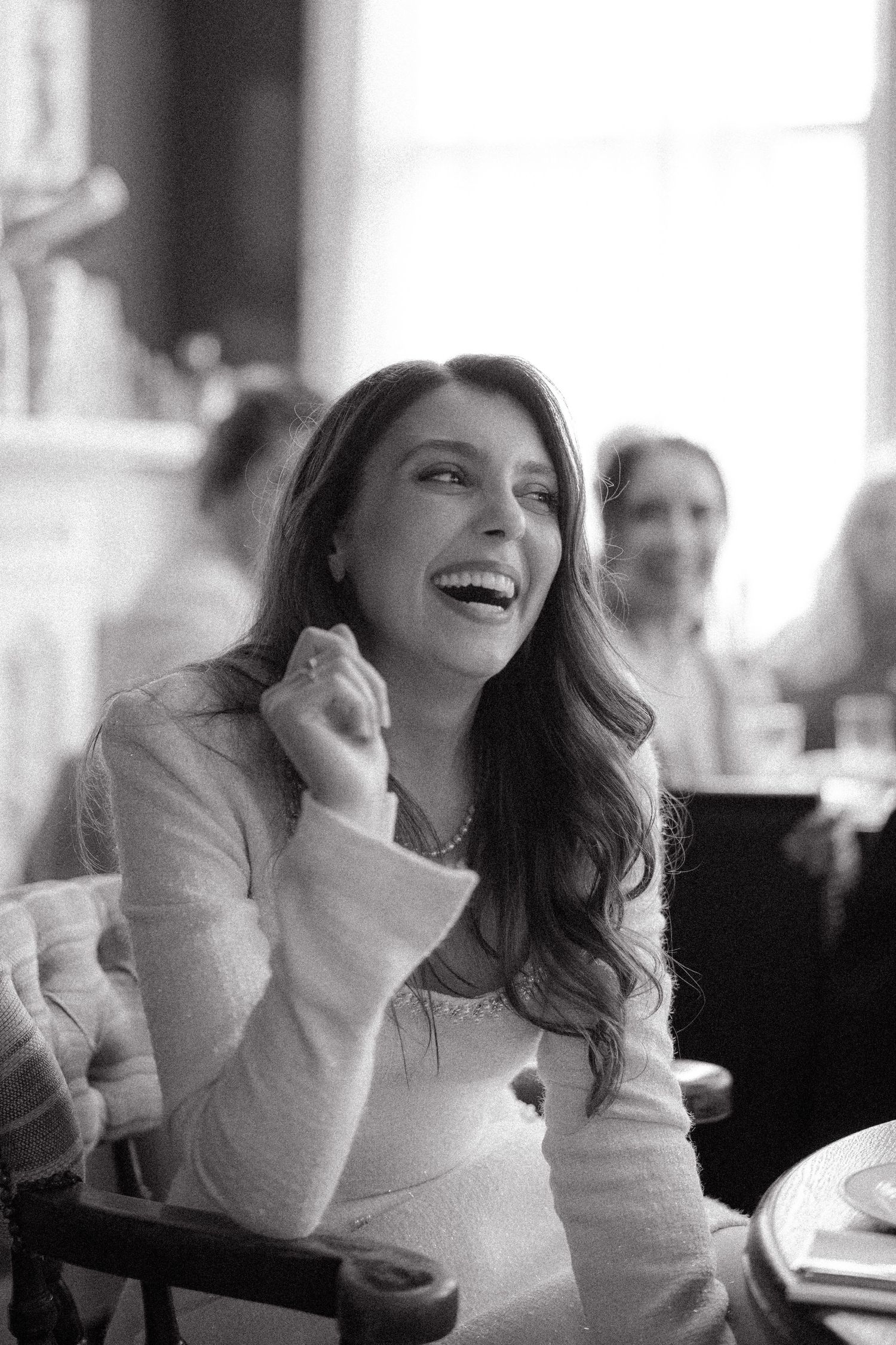 A sequence of black and white photos showing someone laughing joyfully while seated at a table.