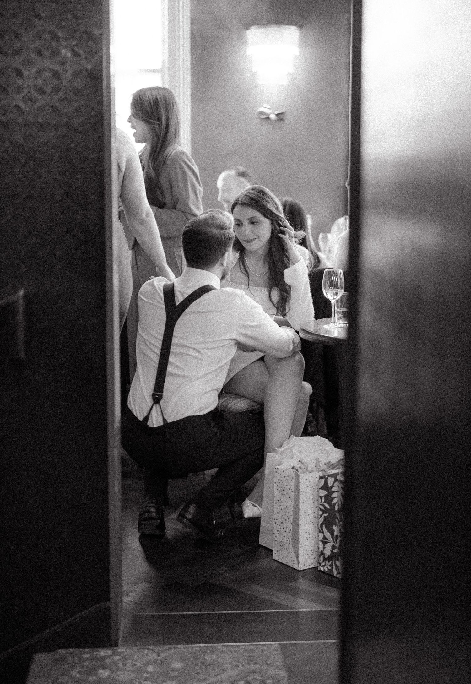 Black and white candid shots through doorway of wedding celebration moments.