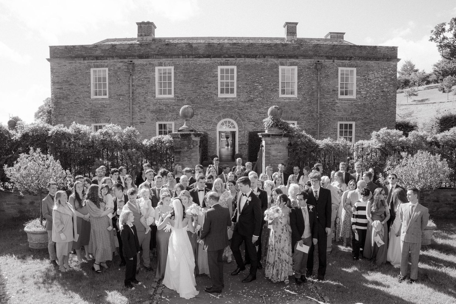 A collection of vintage black and white wedding photographs showing groups gathered outside a brick Georgian mansion.