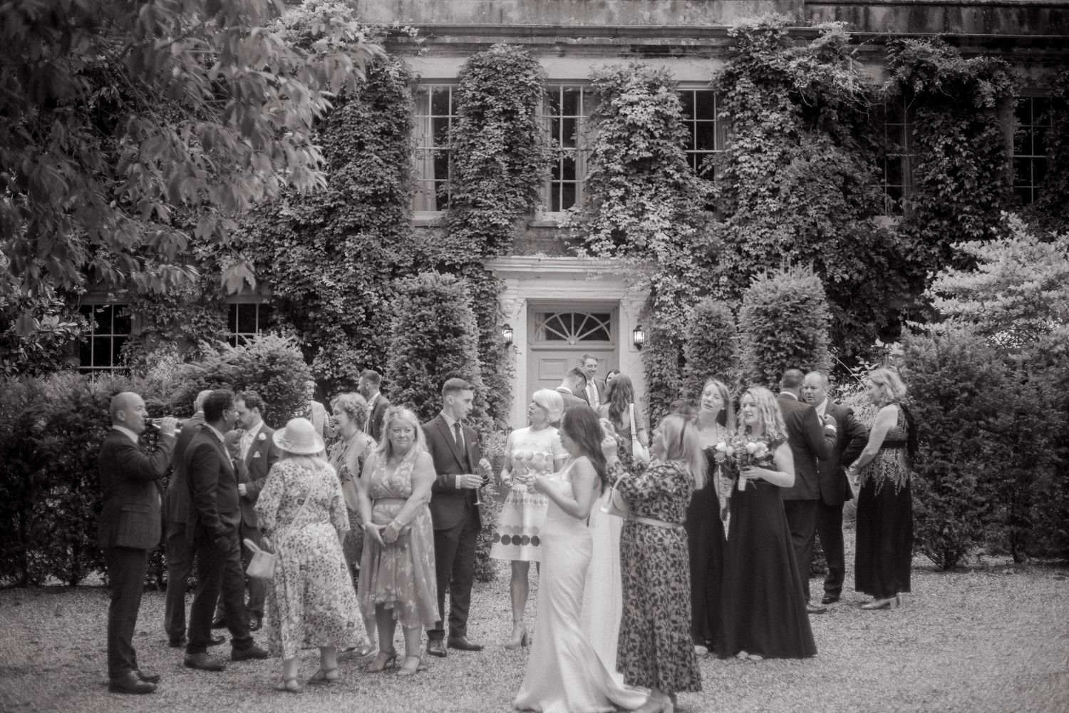 Garden ceremony gathering with guests on manicured grounds of historic estate.
