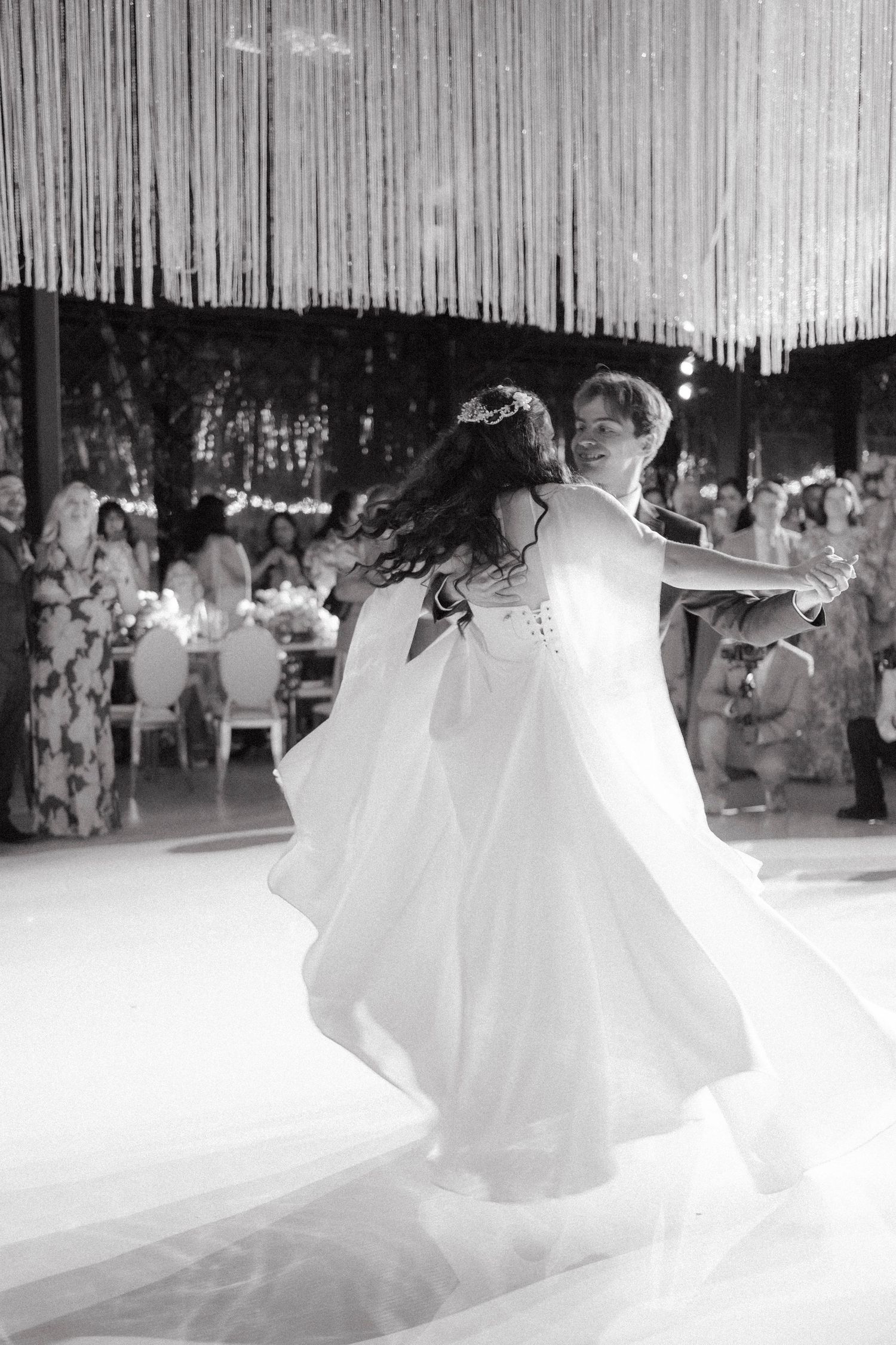 Black and white photo of bride and groom sharing their first dance at an elegant wedding reception.