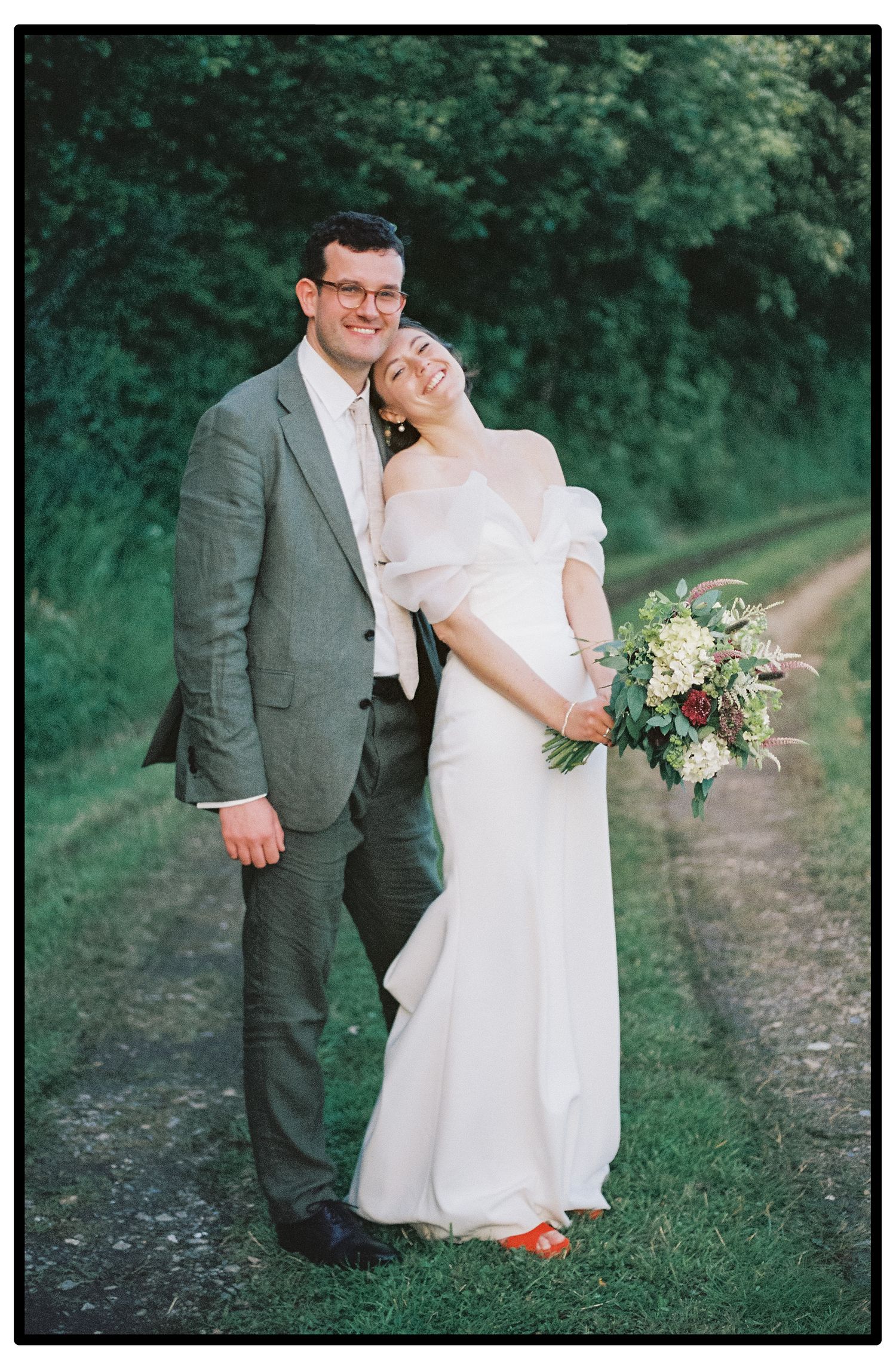 Romantic outdoor wedding portrait on a tree-lined path.