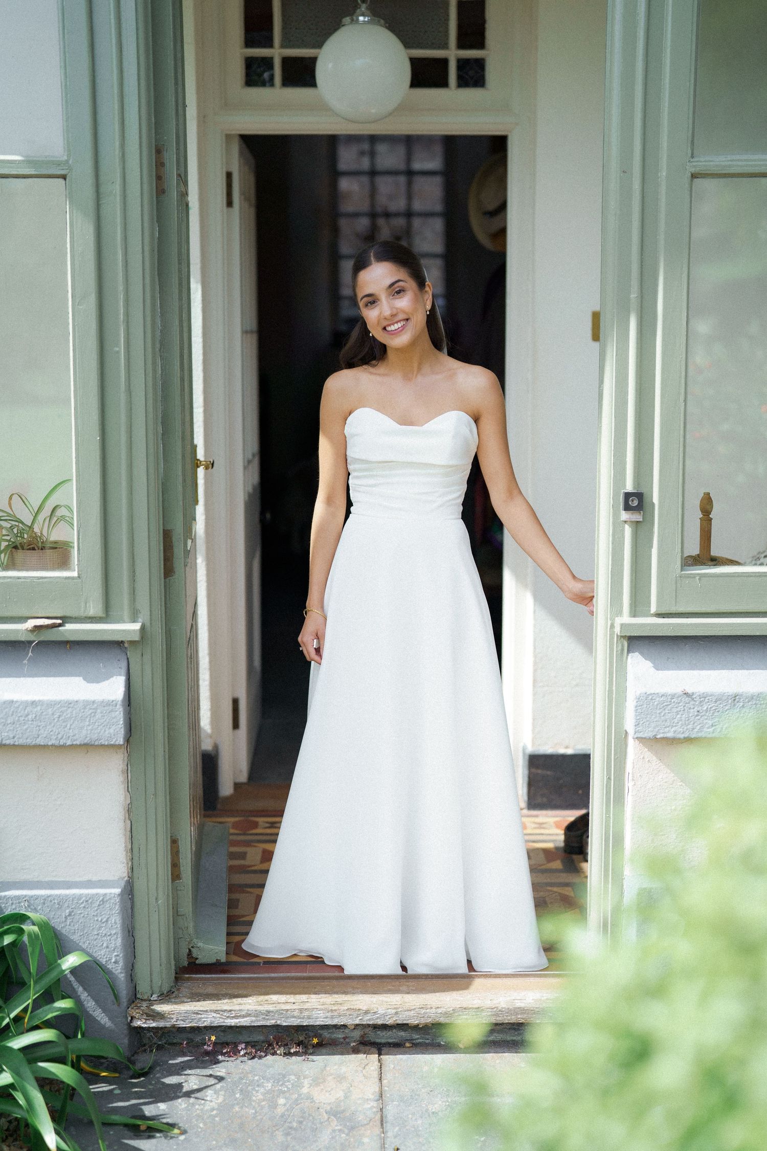 A sequence showing someone in a white dress stepping out onto a porch with greenery visible in the foreground.