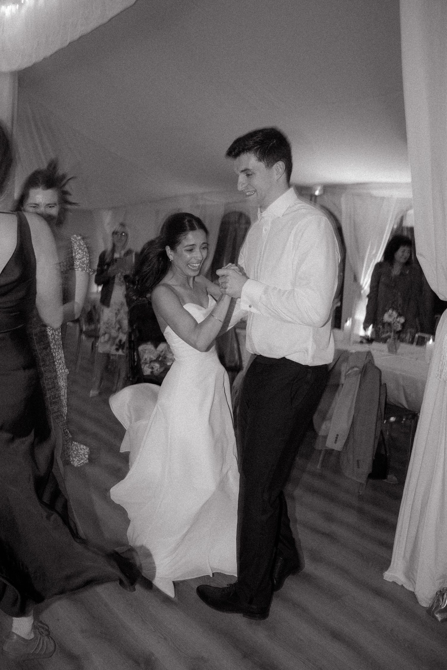 Wedding guests dancing and celebrating at an indoor reception venue.