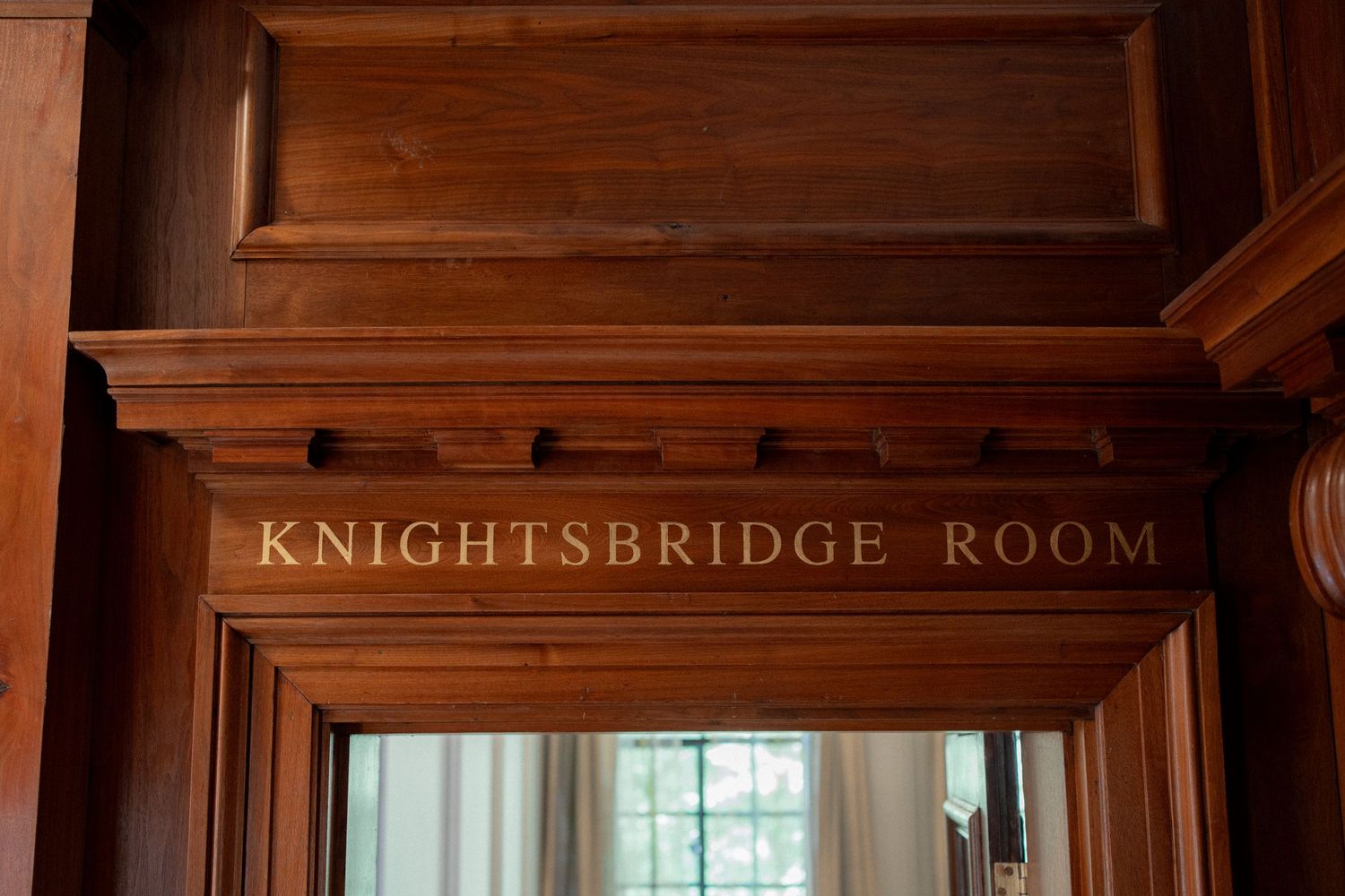 Wooden paneled hallway with Knightsbridge Room signage in an elegant venue.