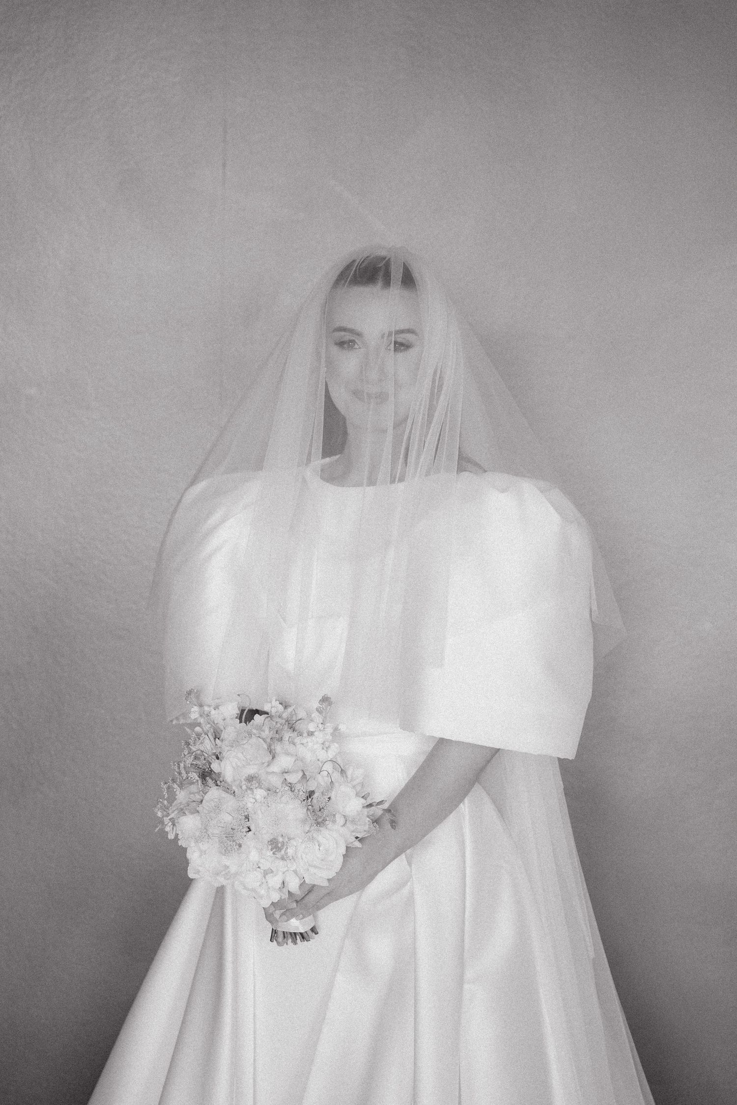 A series of black and white photos showing a bride in a white veil and wedding dress holding a floral bouquet.