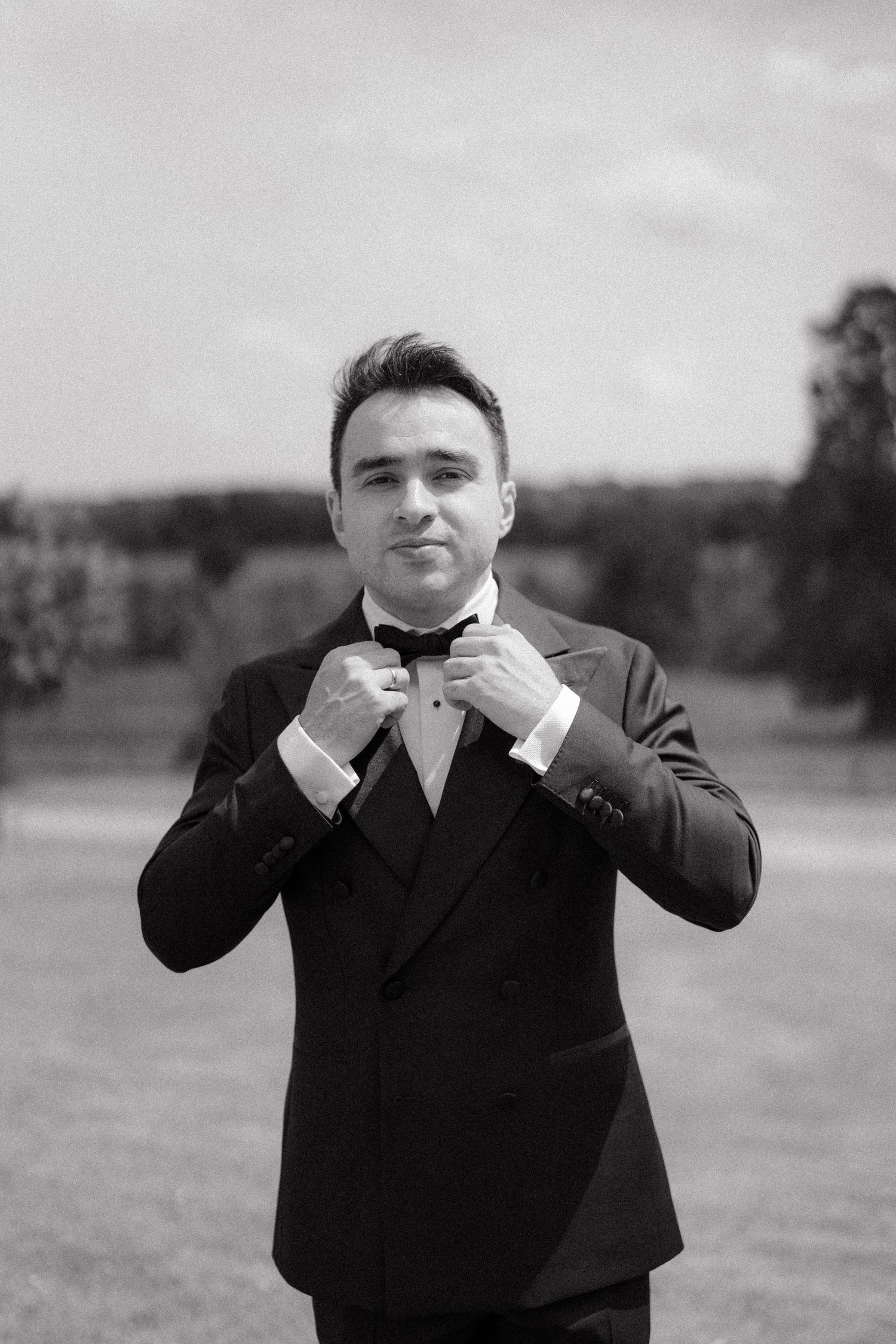 A sequence showing a person adjusting their black bow tie in a formal setting.