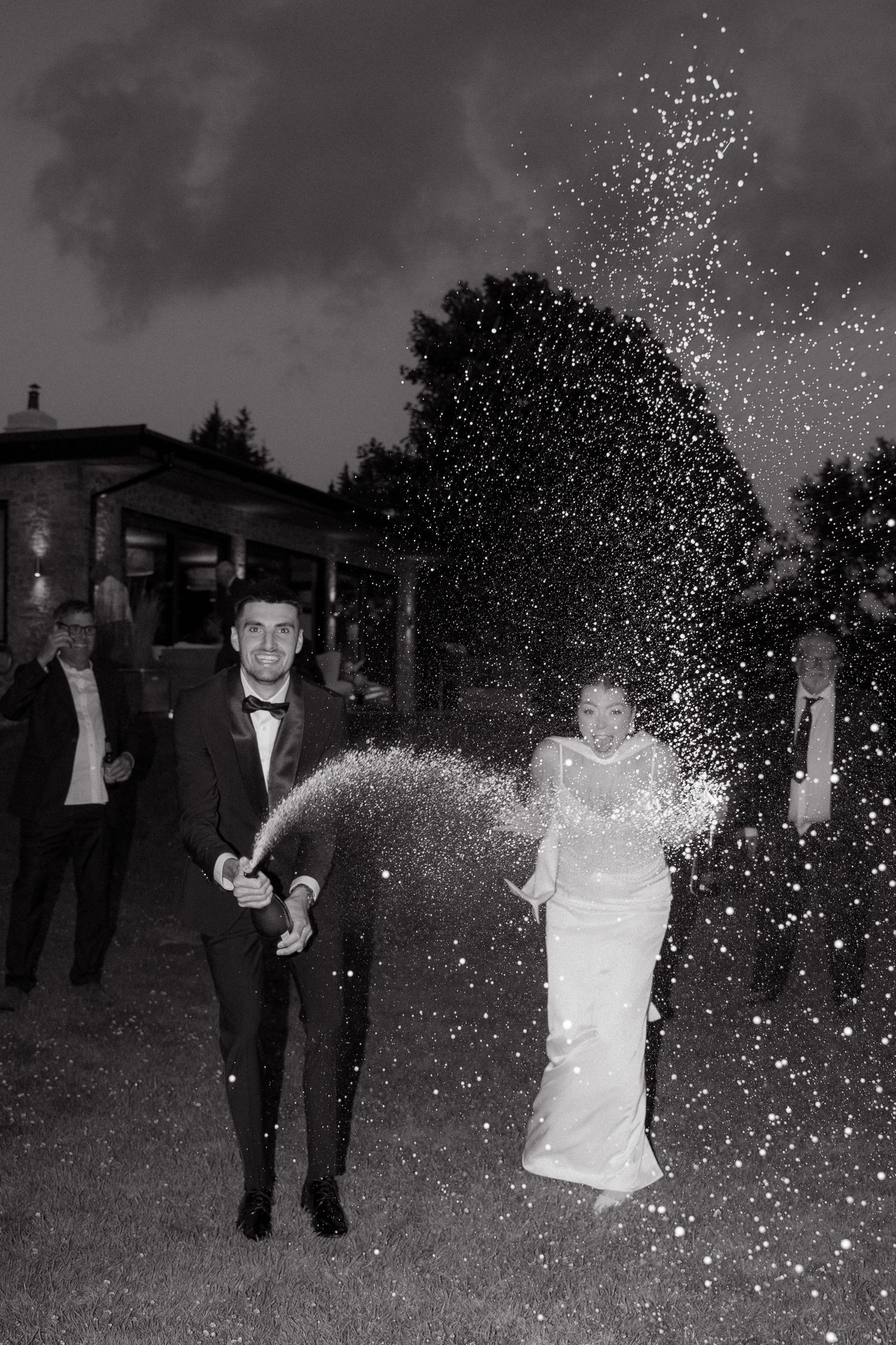 Black and white photo of a couple celebrating with sparklers at night.