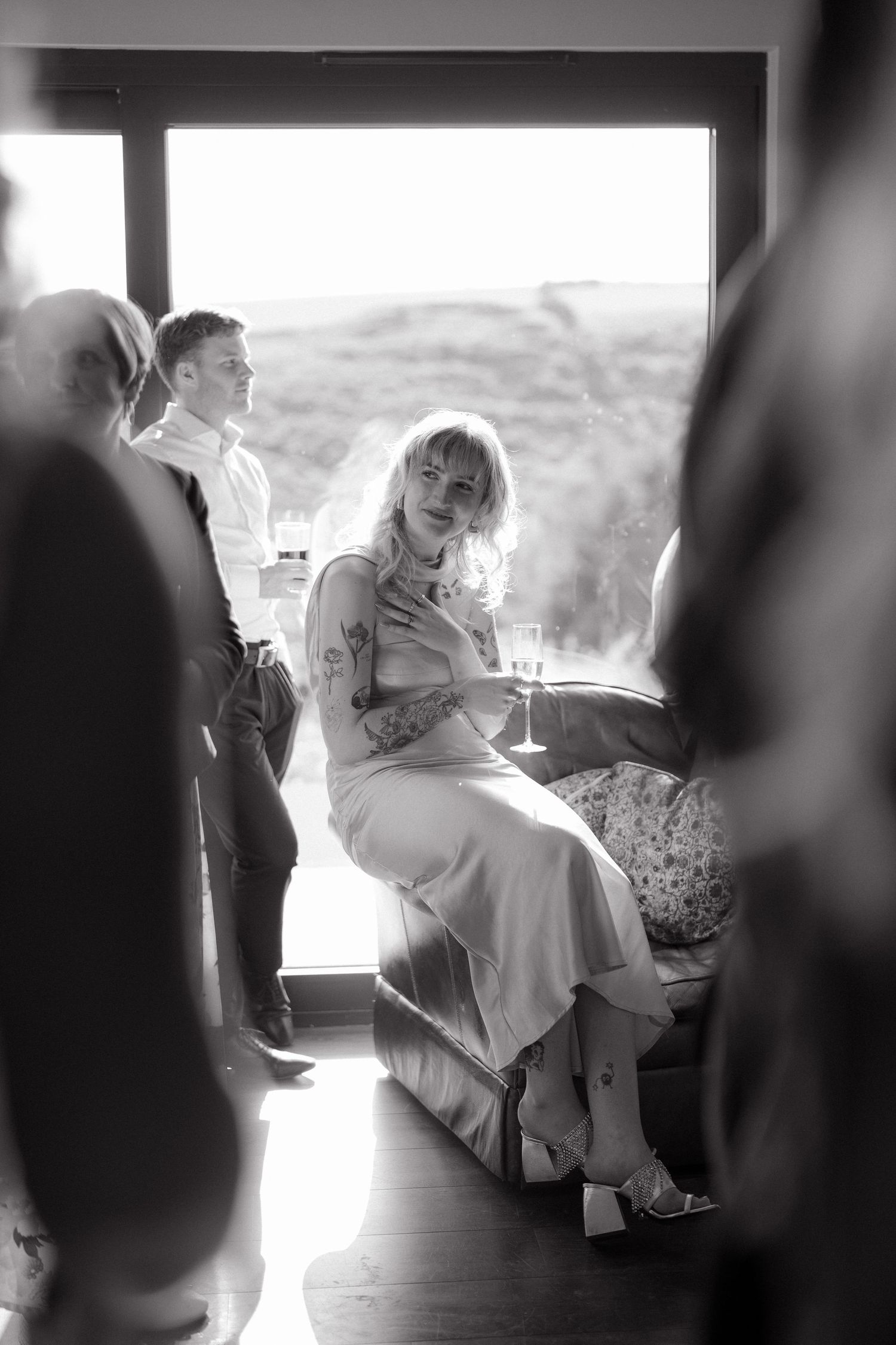 A candid black and white photo of wedding preparations in a sunlit room.