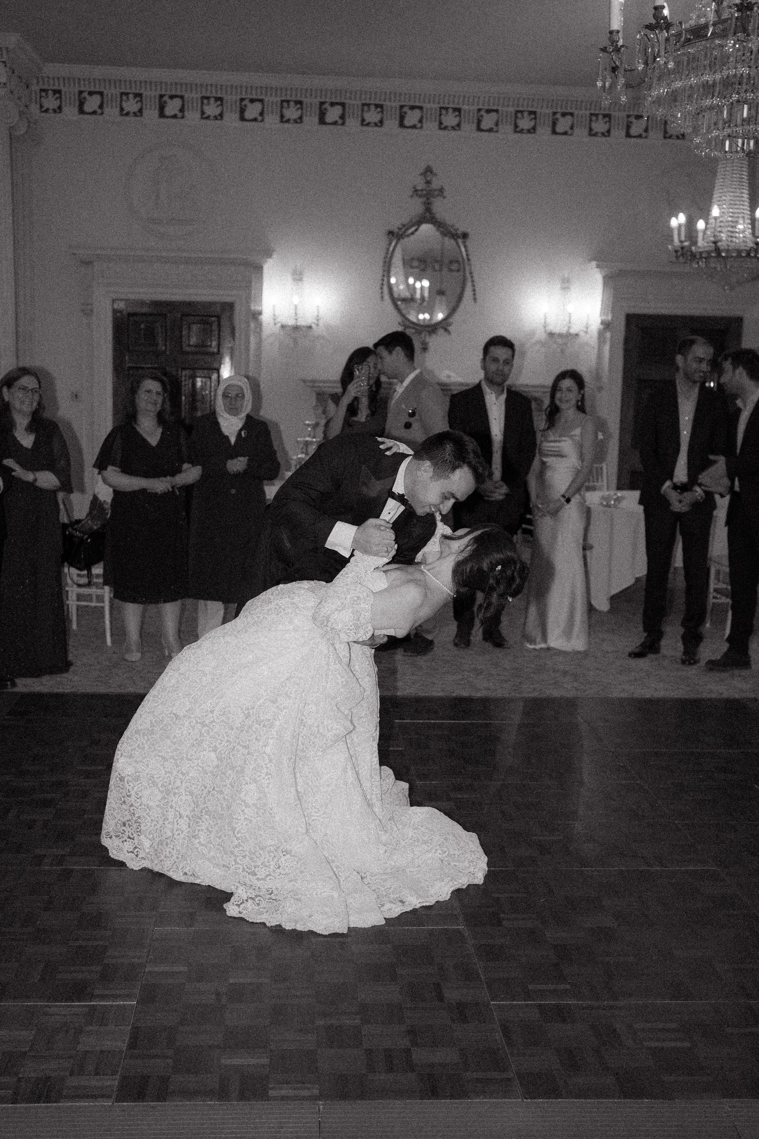 Couple performing romantic dance moves in a grand ballroom with ornate lighting.