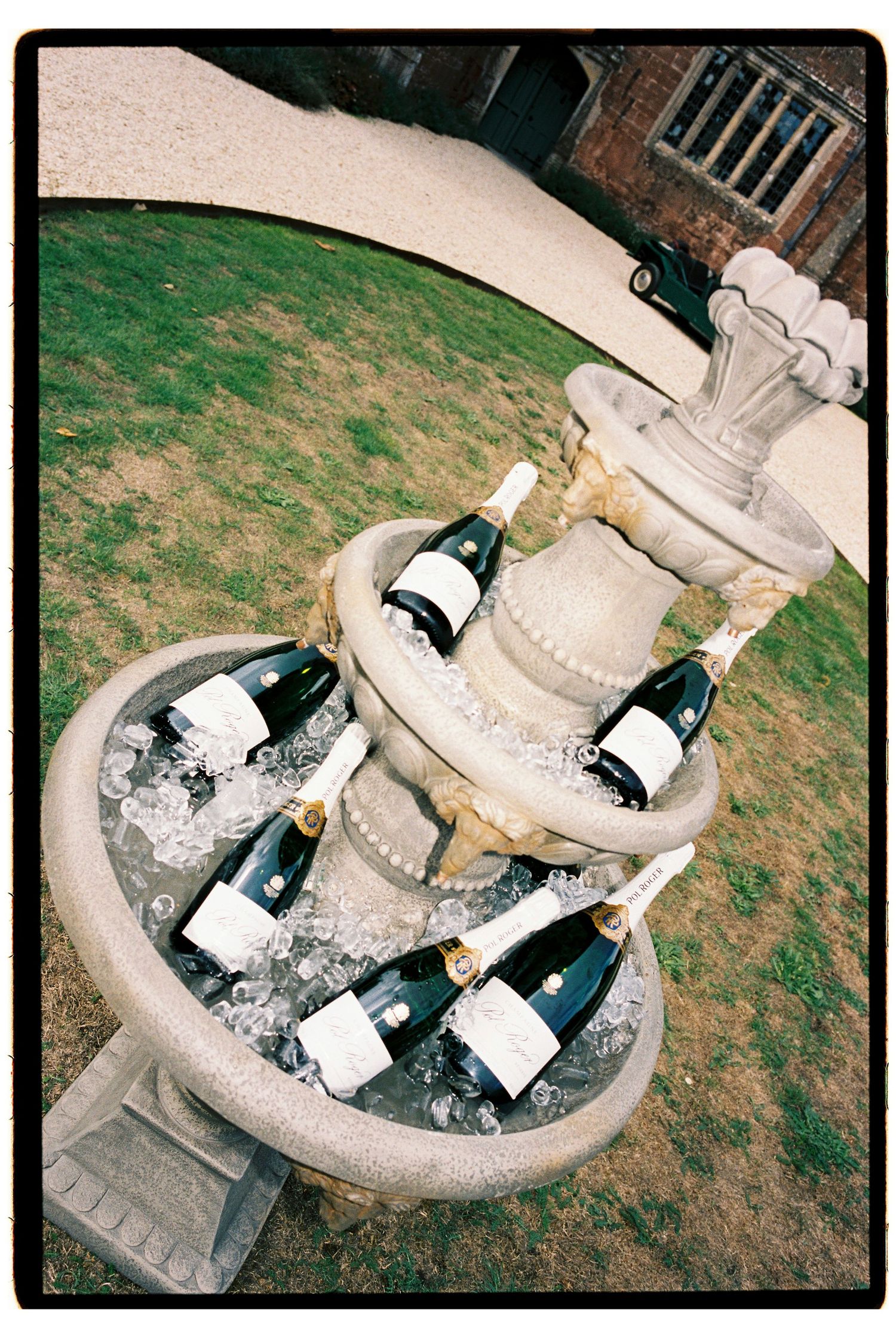 Champagne bottles chilling on ice in a stone fountain at a wedding.
