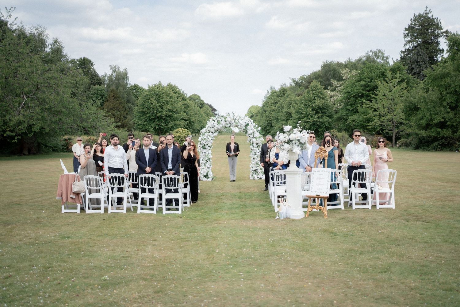 Panoramic view of white chairs set up for an outdoor wedding ceremony.