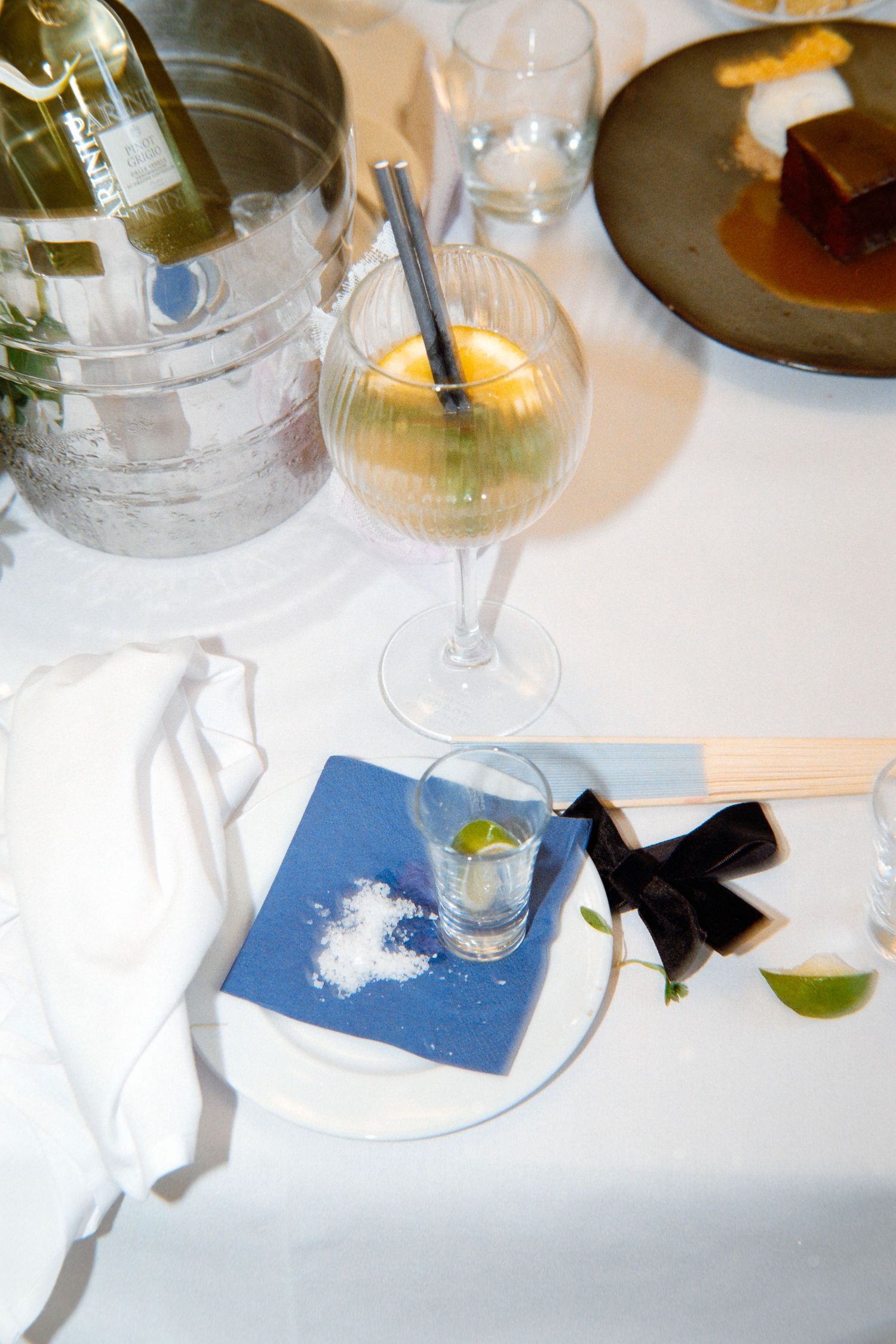 A series of wine glasses on a white tablecloth with blue coasters arranged in a restaurant setting.