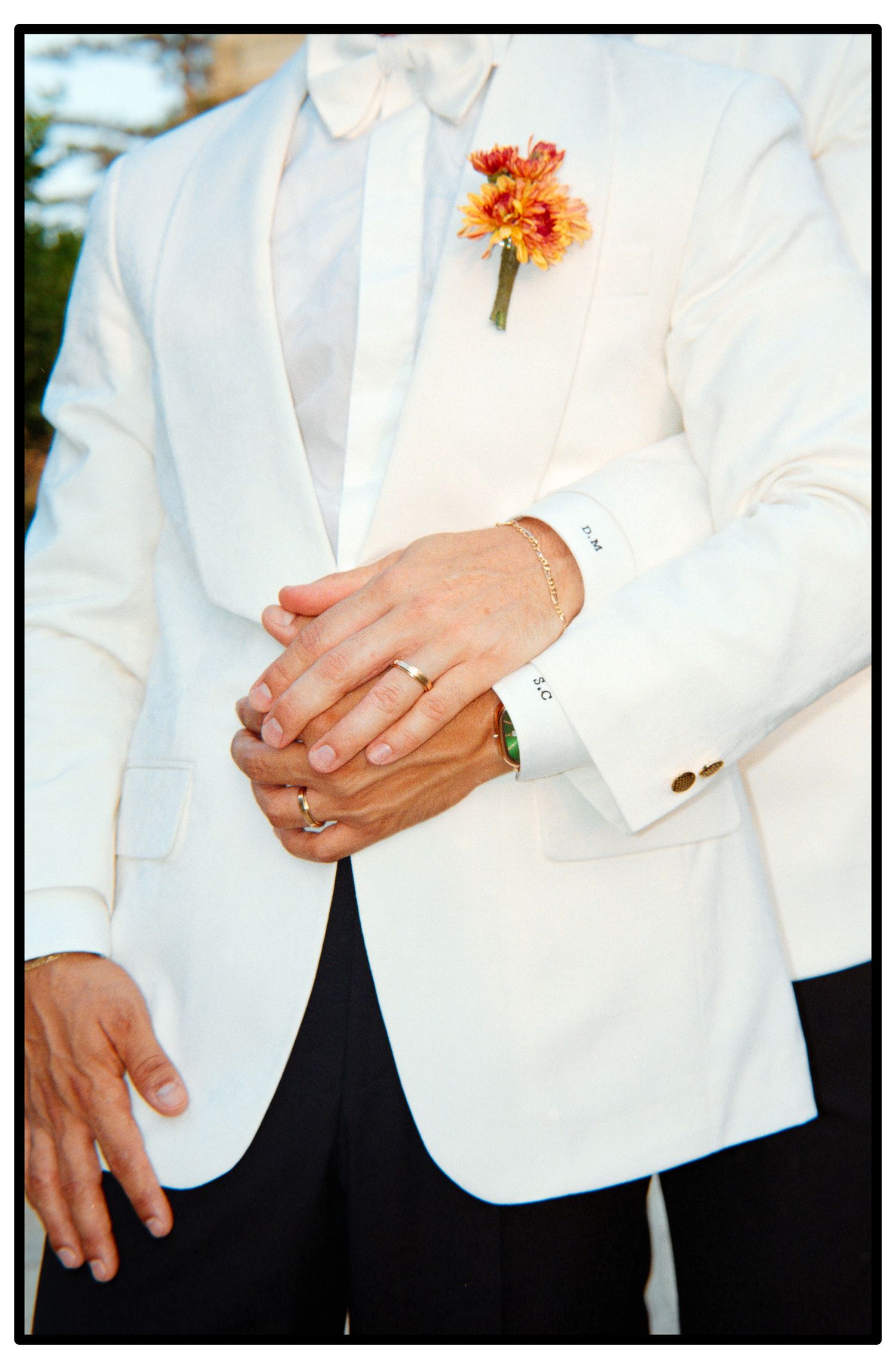 Close-up shots of white tuxedo jackets with orange floral boutonnieres and black pants.