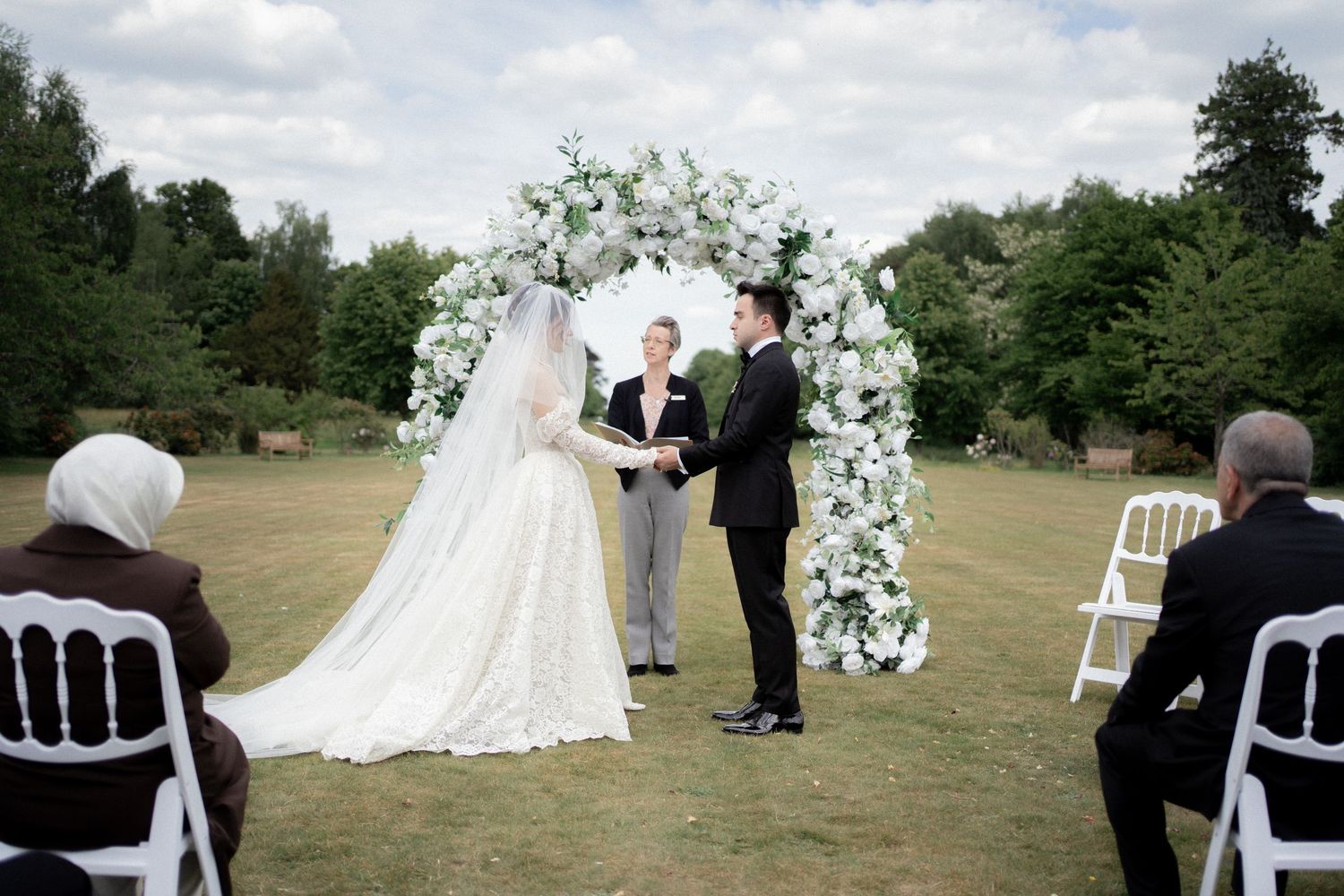Wide shots of an elegant outdoor wedding ceremony setup with white chairs.