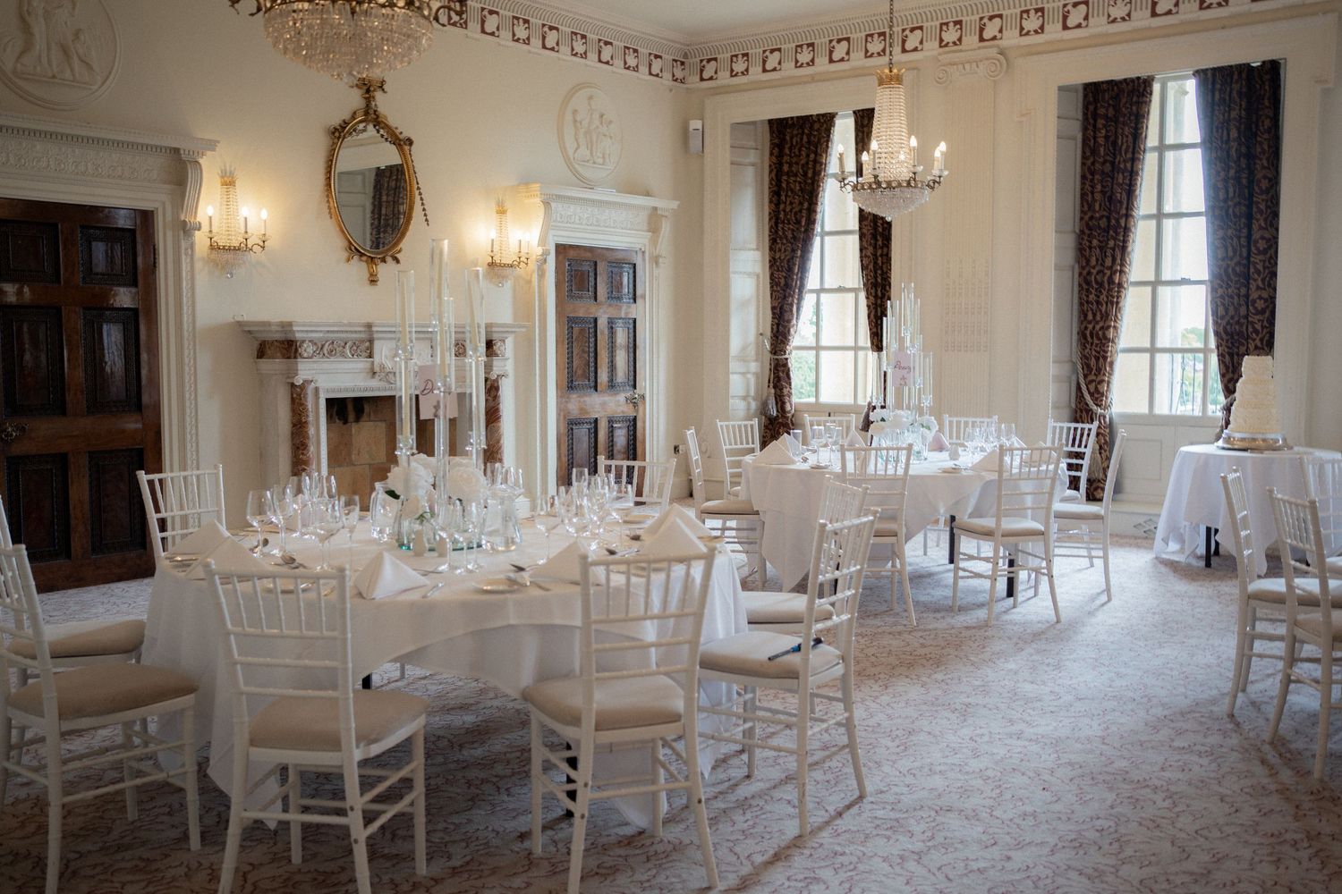 Elegant white wedding reception venue with crystal chandeliers and ornate molding details.