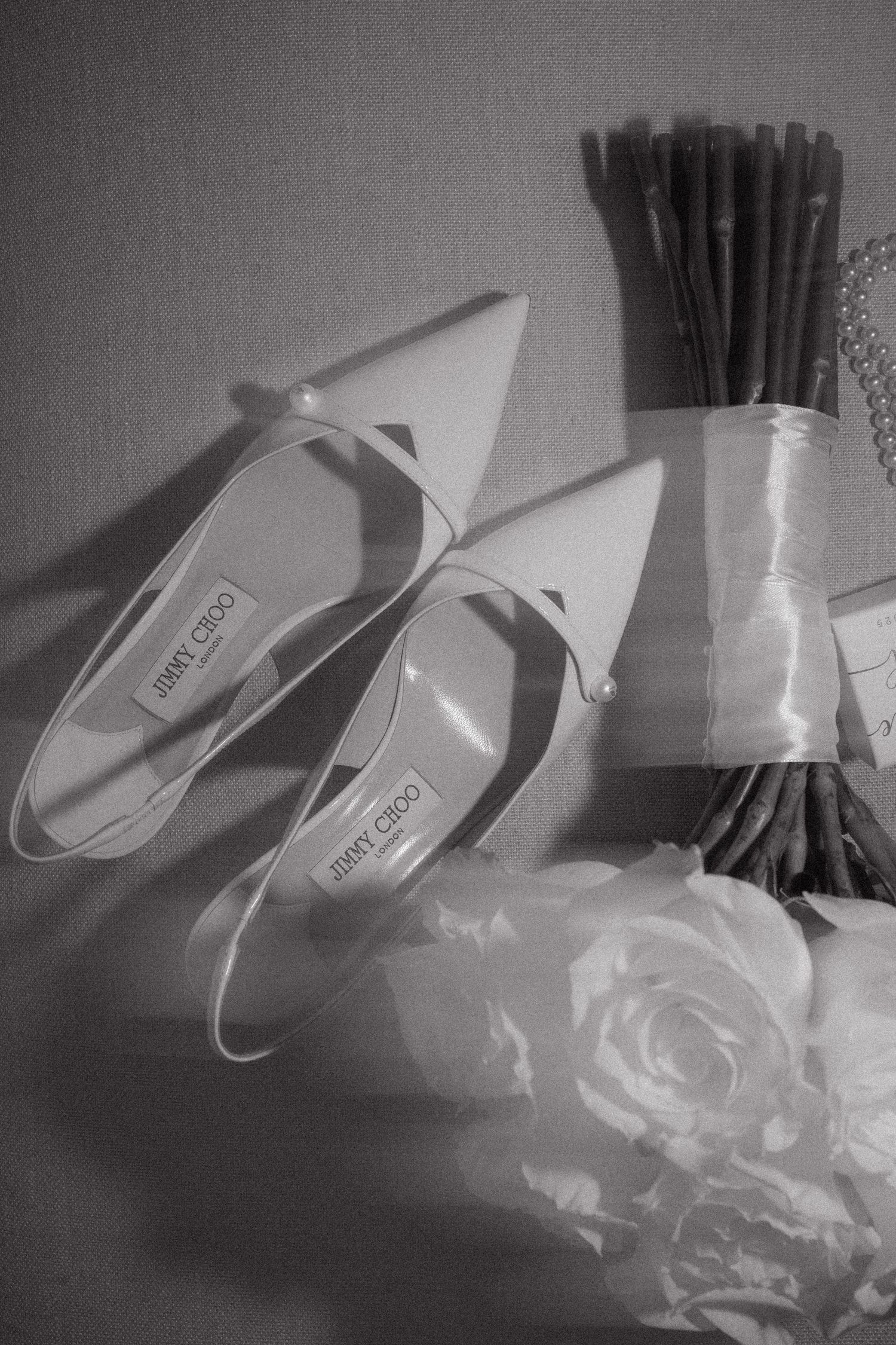 Black and white still life of wedding shoes arranged artistically.