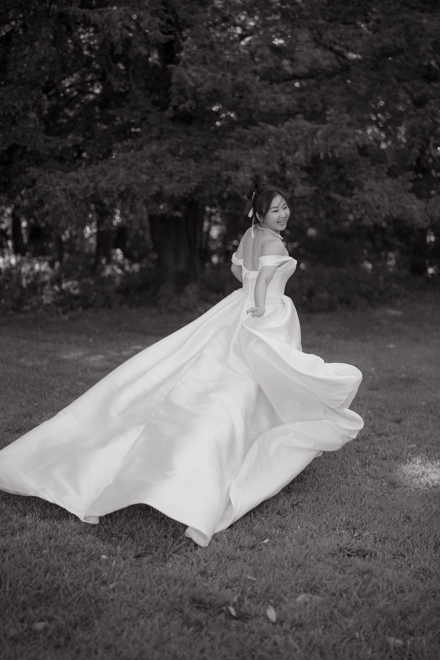 Black and white series showing a flowing wedding dress twirling in an outdoor garden setting.