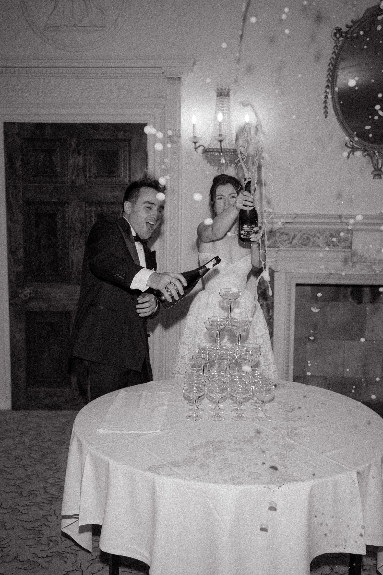 Champagne being poured into crystal glass tower at formal wedding celebration.